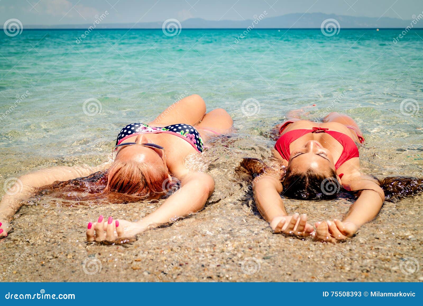 Tijd te genieten van. Twee meisjes die op het strand ontspannen Zij lounging en zonnebaden op de kust in het overzees Achter mening