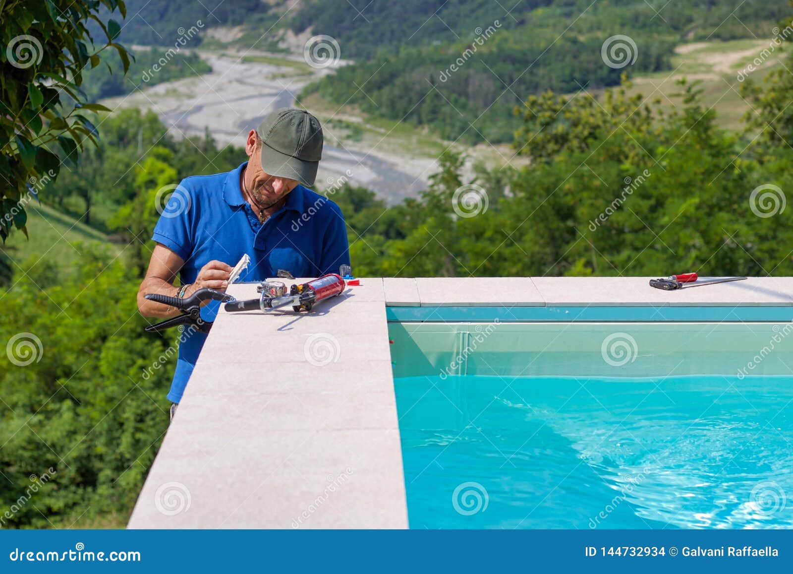 Tiler Working In A Garden Building The Edge Of A Pool Stock Photo