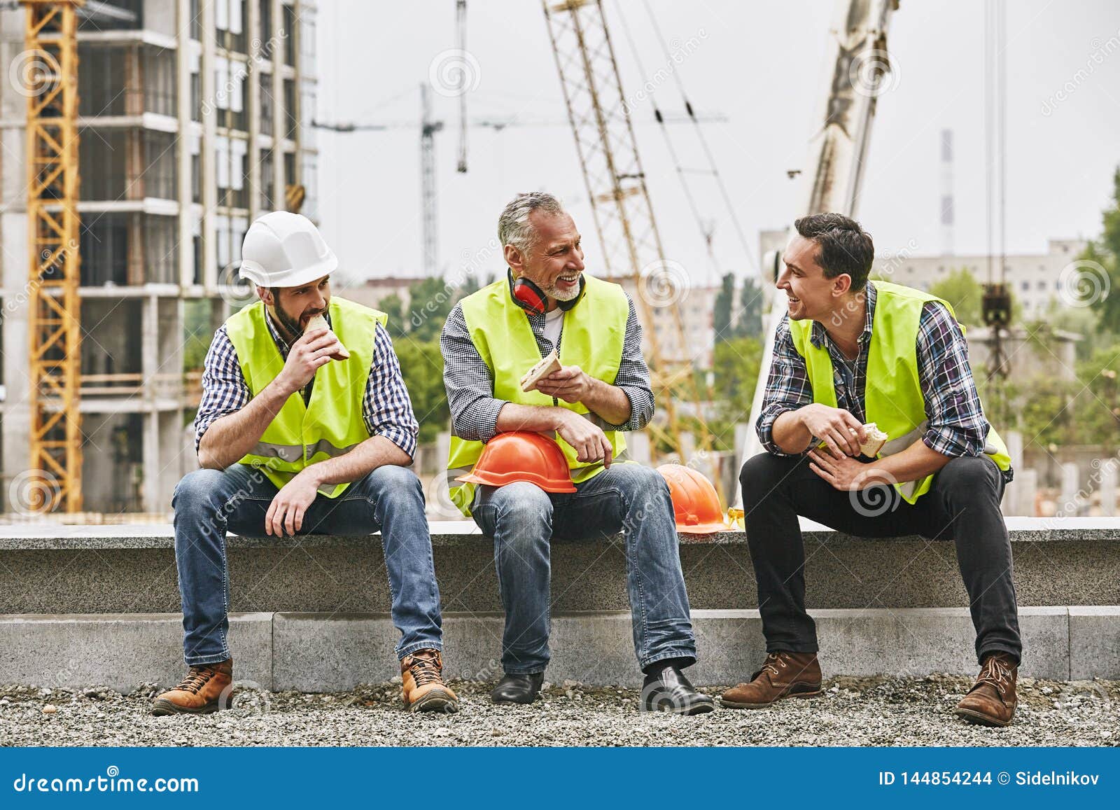 Time for a Break. Group of Builders in Working Uniform are Eating