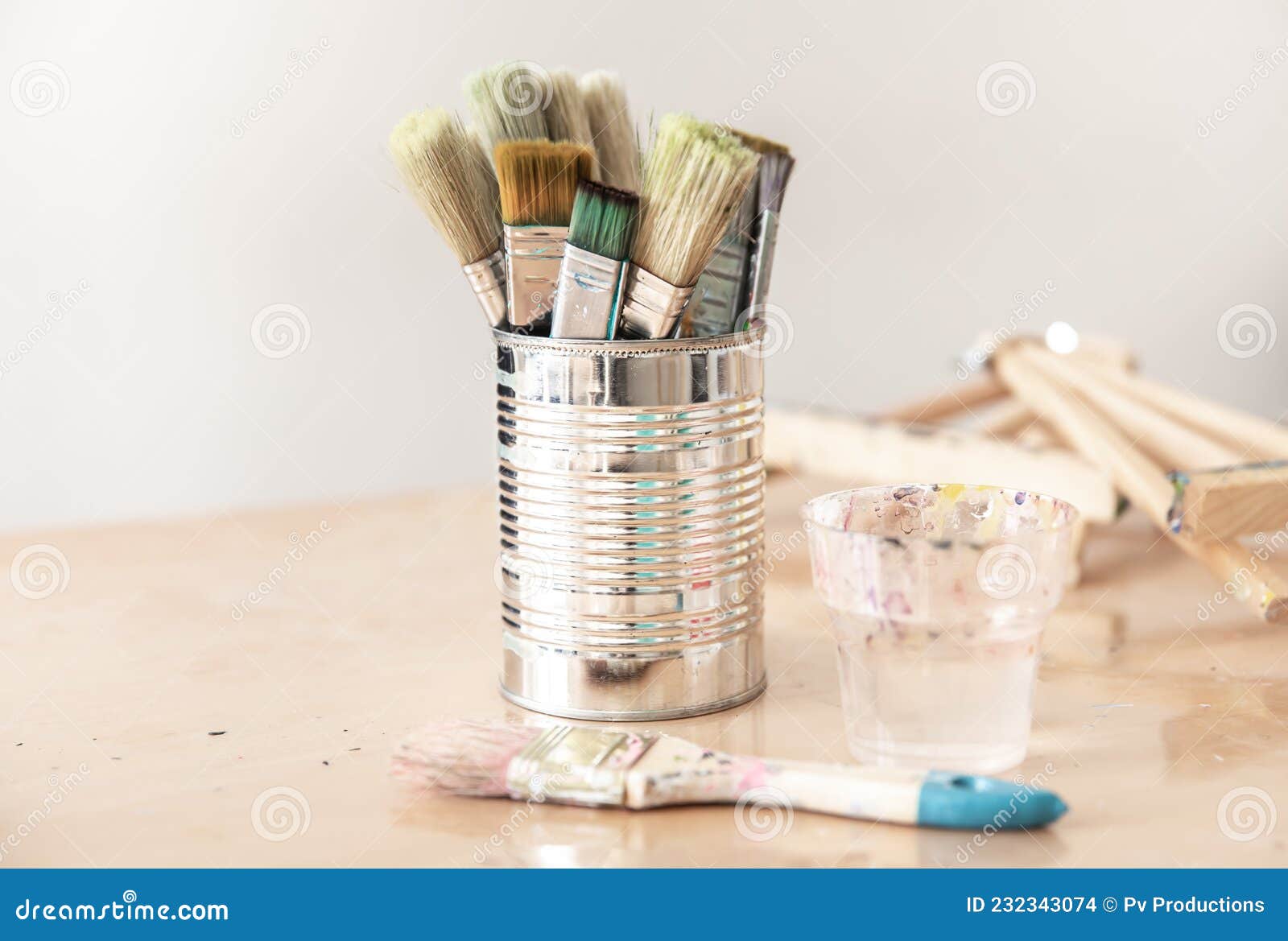 Tin Can with Paint Brushes on a Table on a Blurred Background