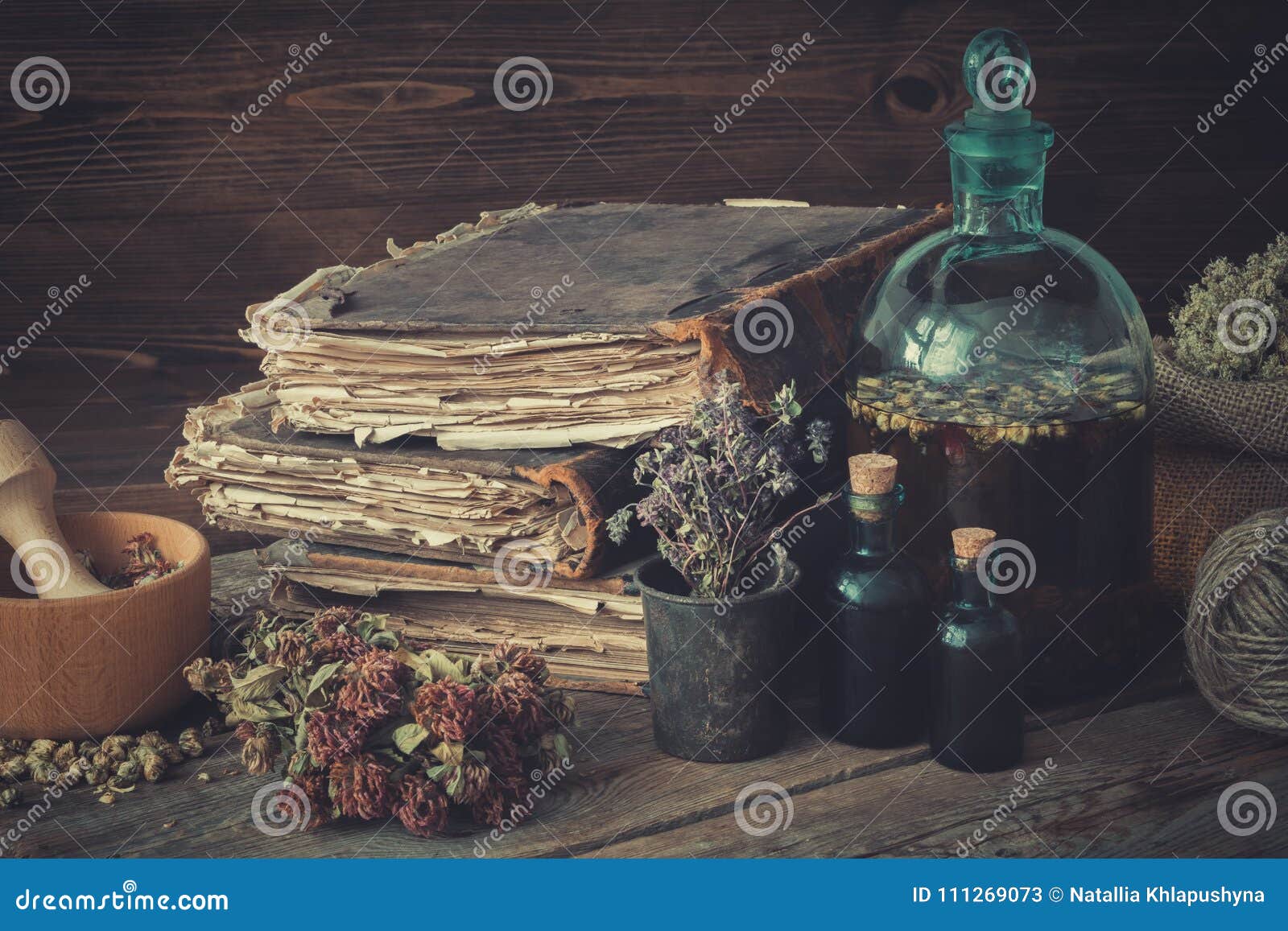 tincture bottles, assortment of dried healthy herbs, old books, wooden mortar, sack of medicinal herbs. herbal medicine.