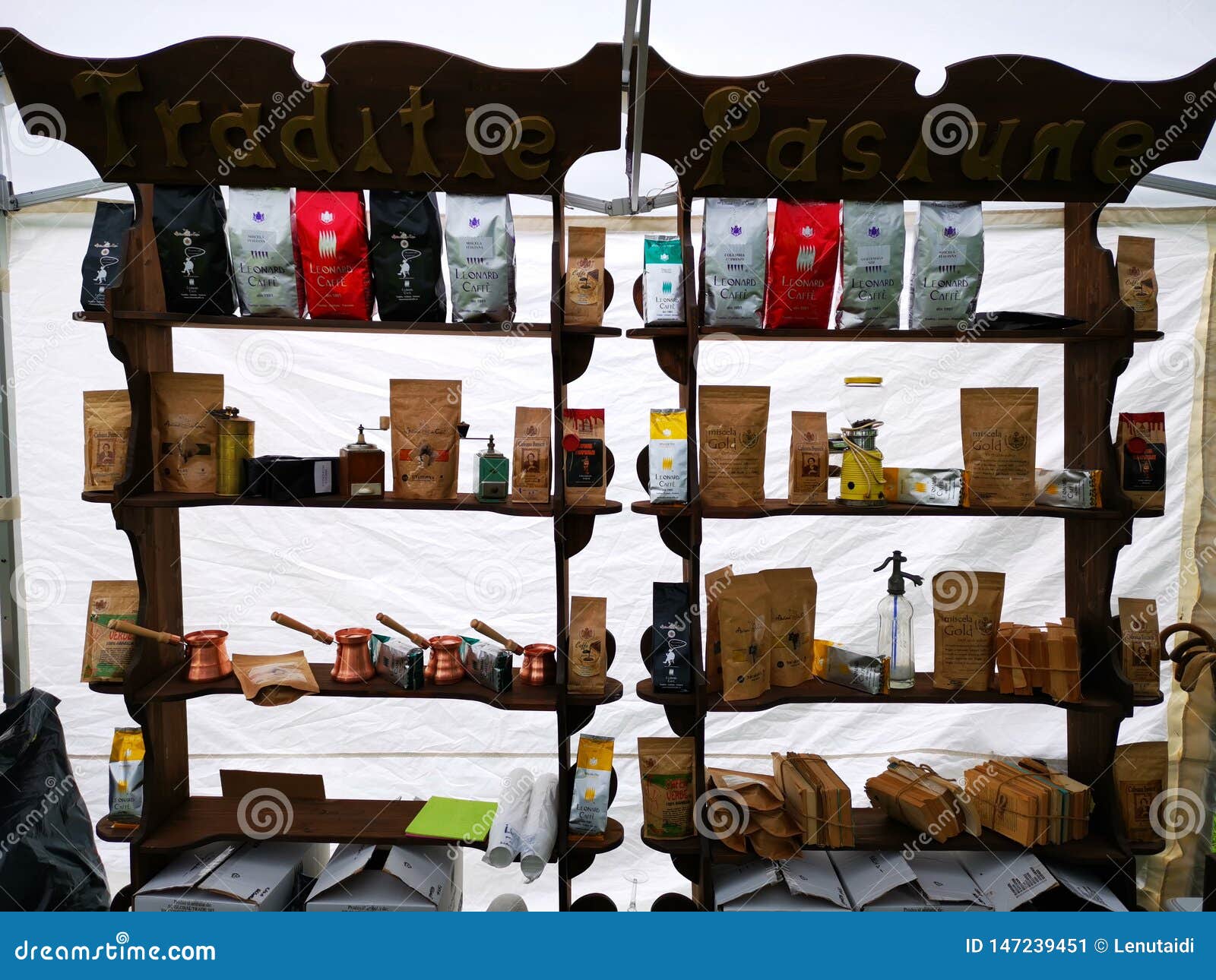 Tipi e sapori differenti di chicchi di caffè sugli scaffali di legno ed altri oggetti - bollitori di rame