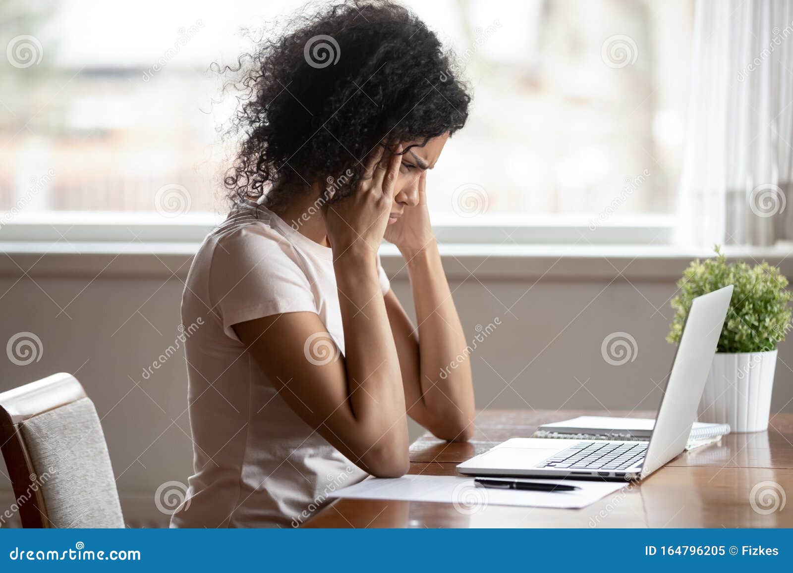 unwell biracial woman suffer from headache working at laptop
