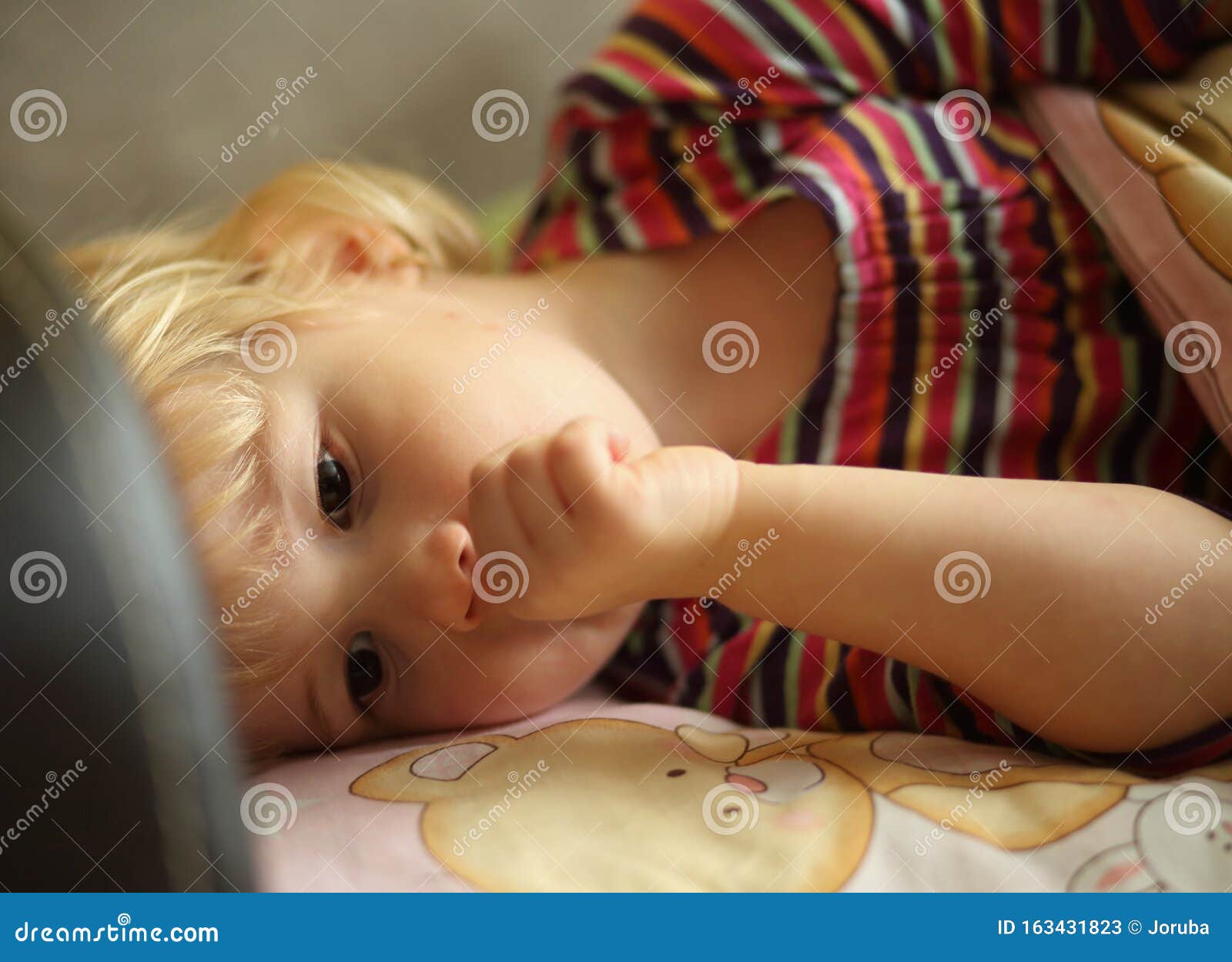 tired child on bed suck finger