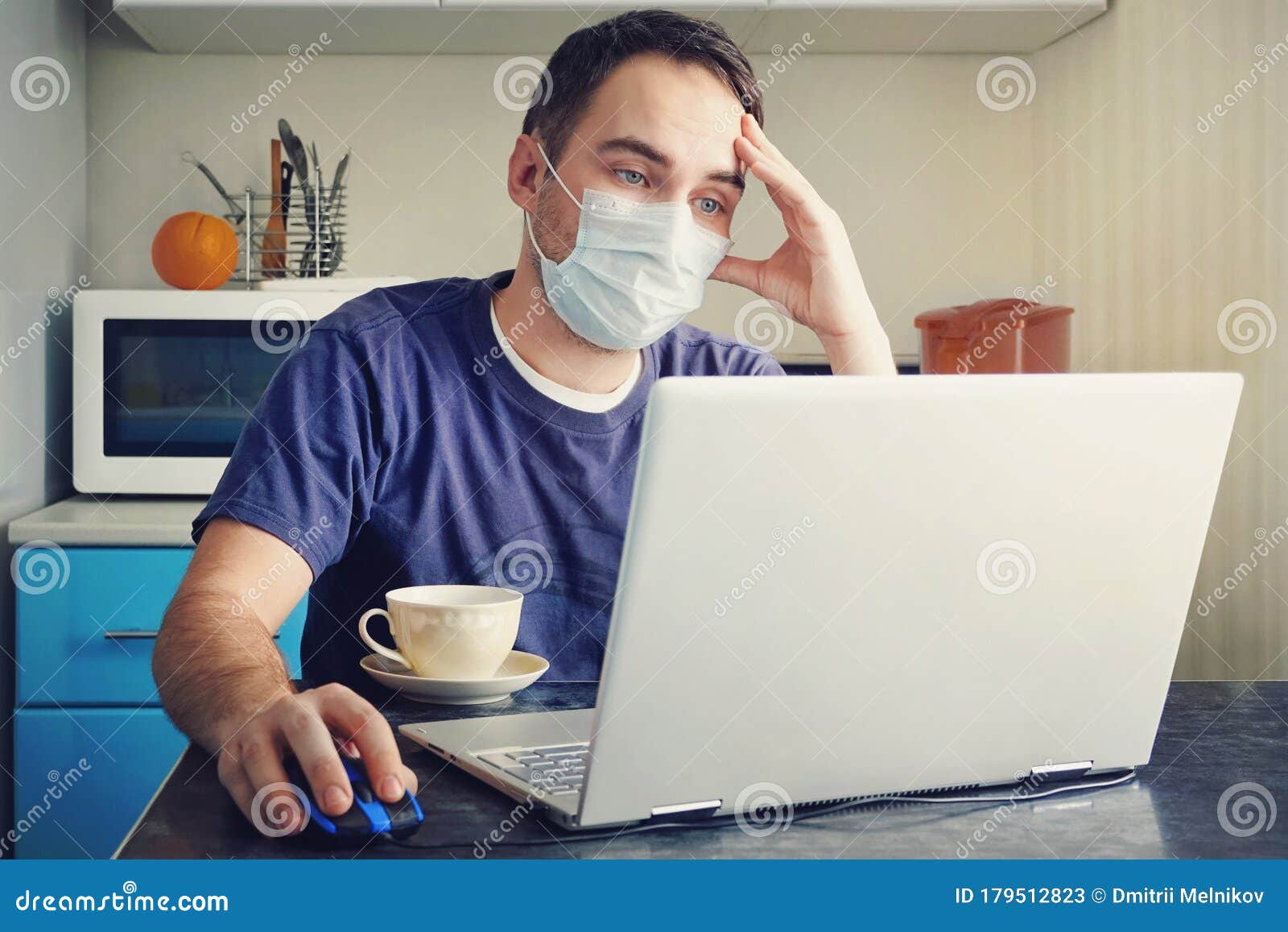 a tired employee works from a home office. young man wearing medical face mask at work from home office due to corona