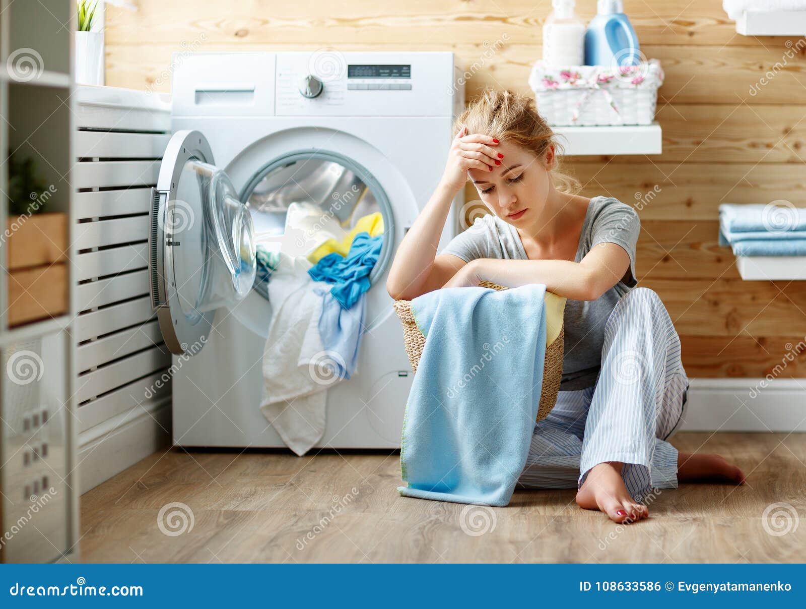 tired housewife woman in stress sleeps in laundry room with washing machine