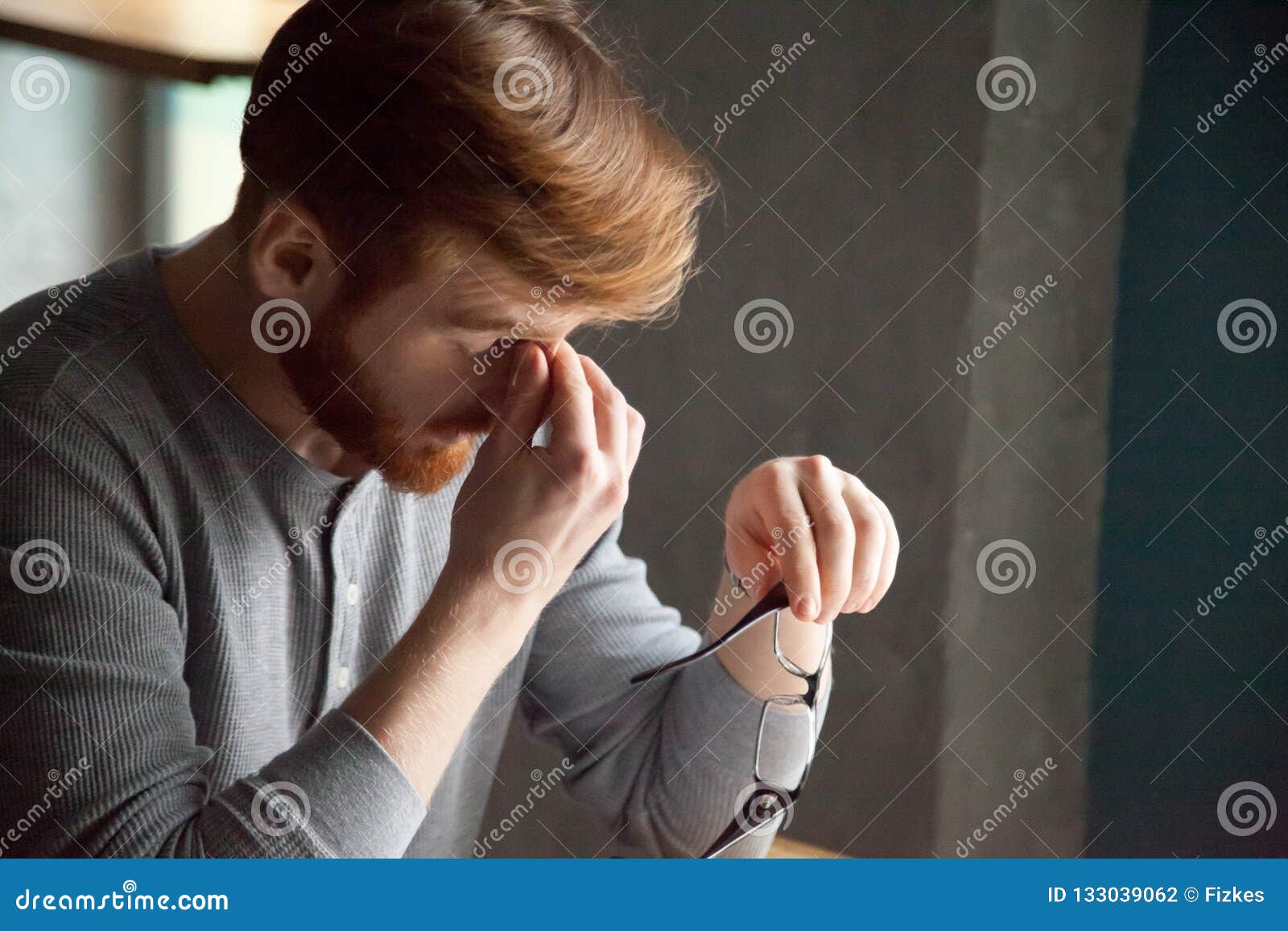 tired millennial man massaging nose feeling fatigue from work
