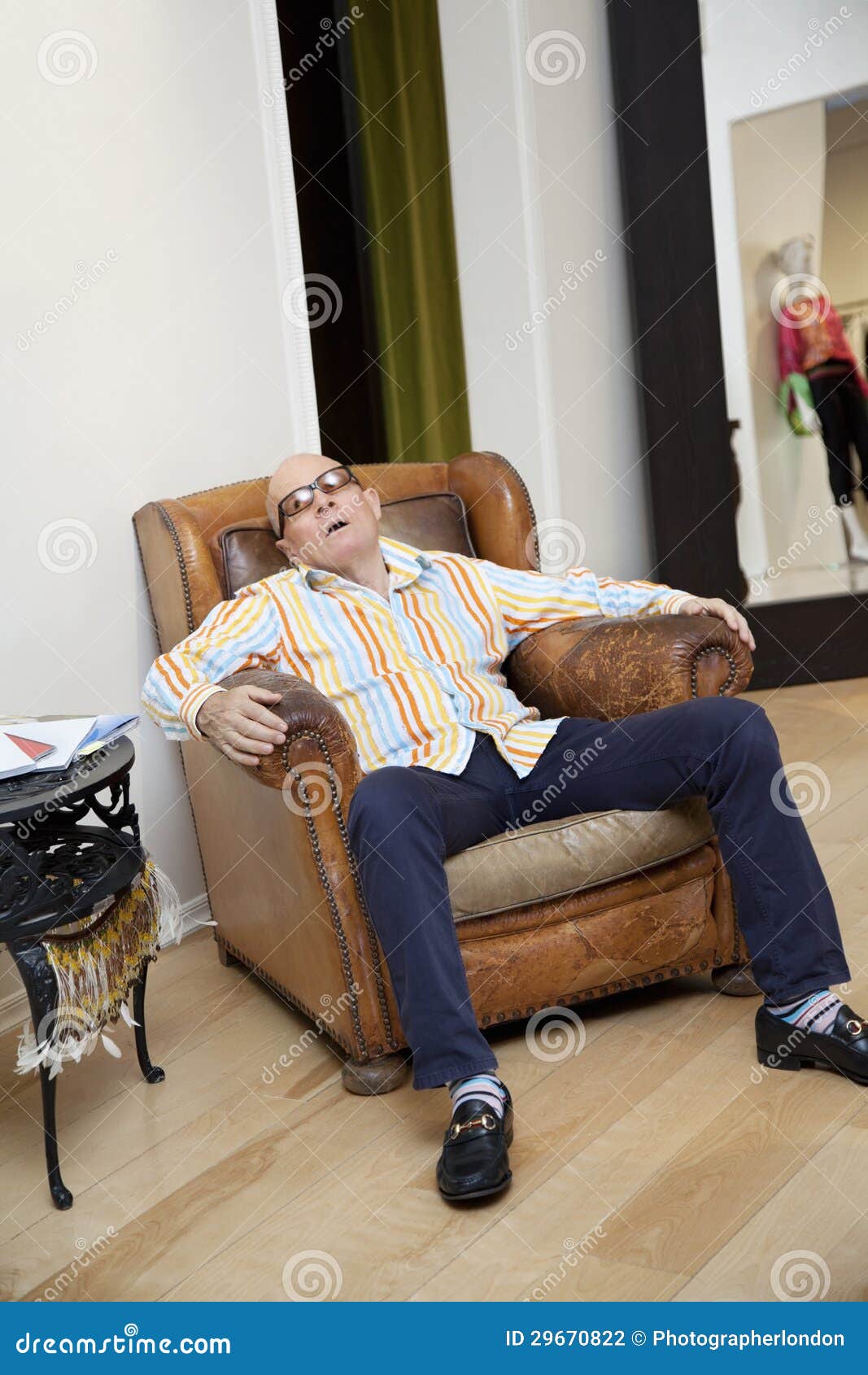 Tired Senior Man Sitting On Armchair In Fashion Boutique Stock Photo