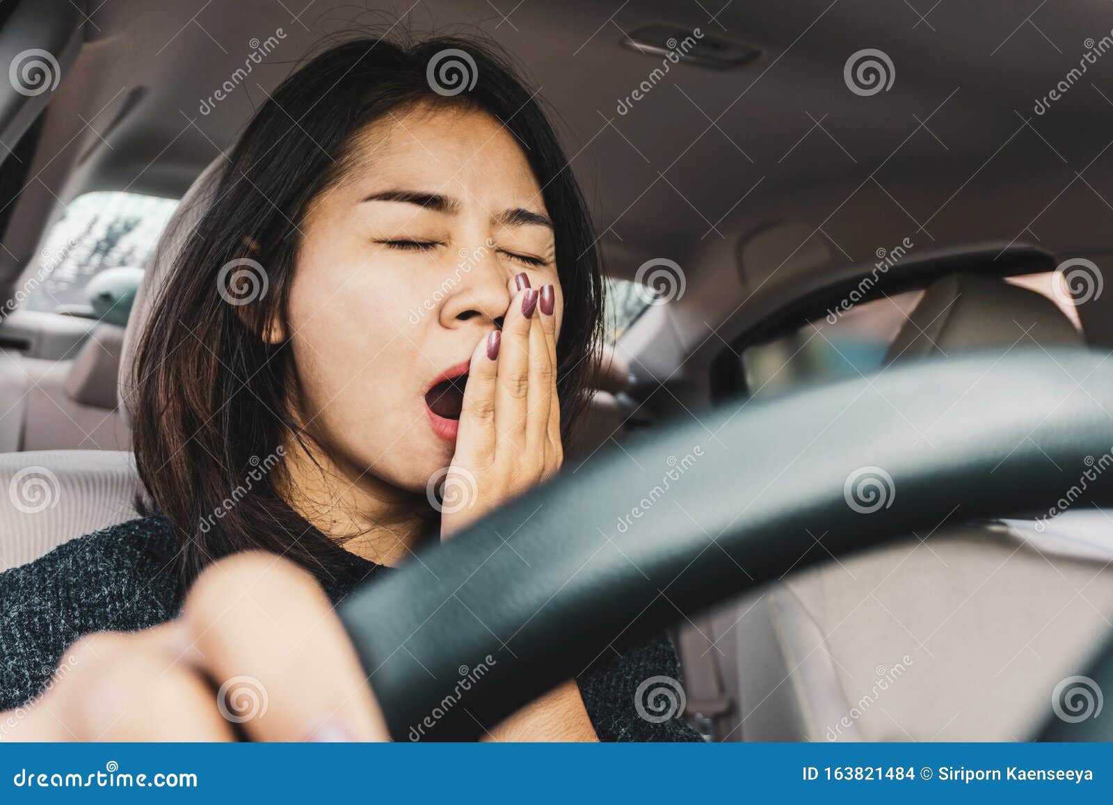 tired sleepy asian woman yawning during driving car