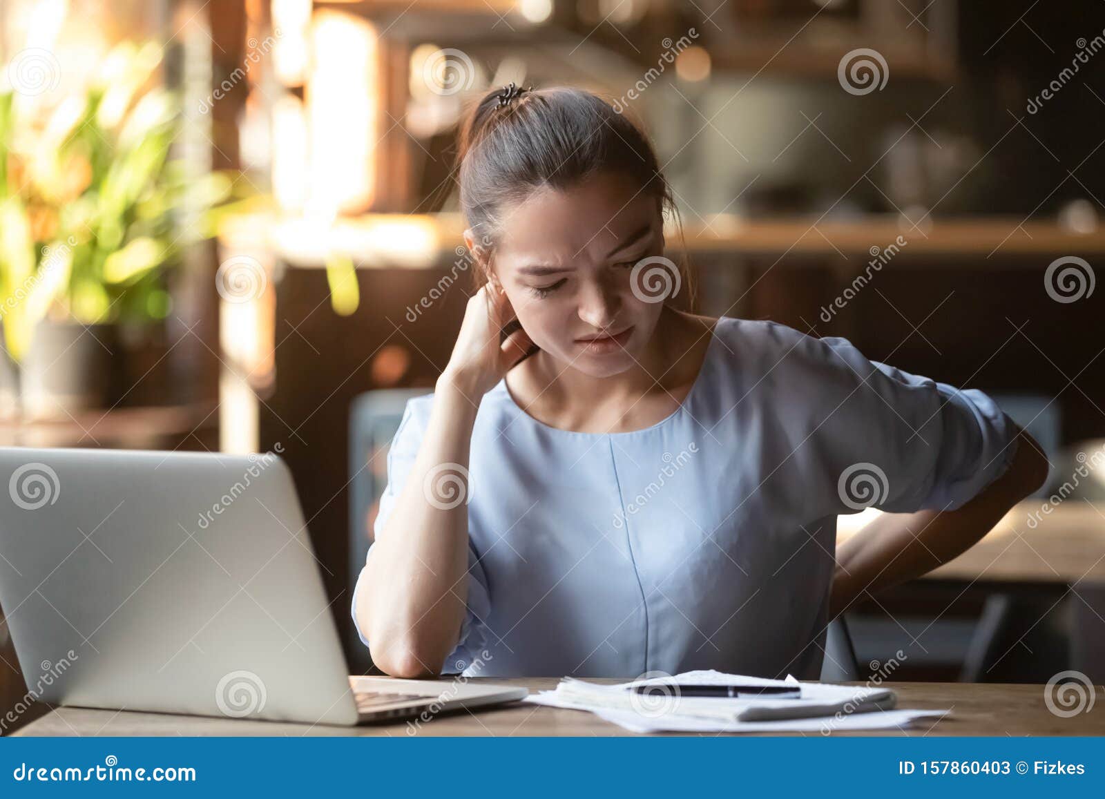 tired woman feeling pain after sedentary computer work in cafe