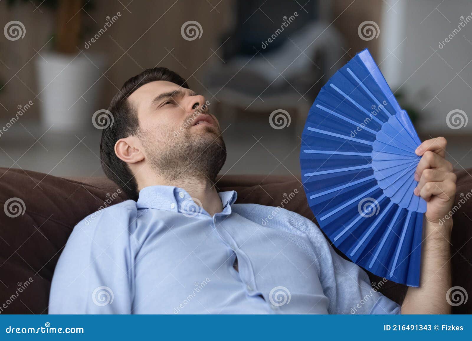 tired young man wave with hand fan suffer from heatstroke