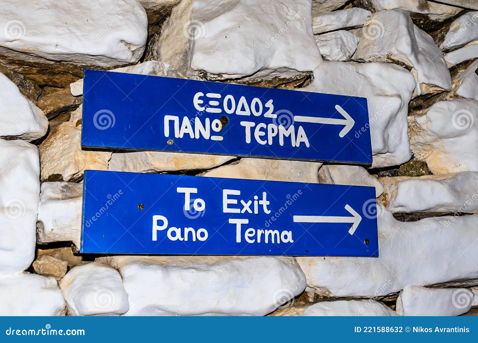 to exit pano terma funny blue signs attached on the stone wall in syros island, greece. exit is all the way up on the right.