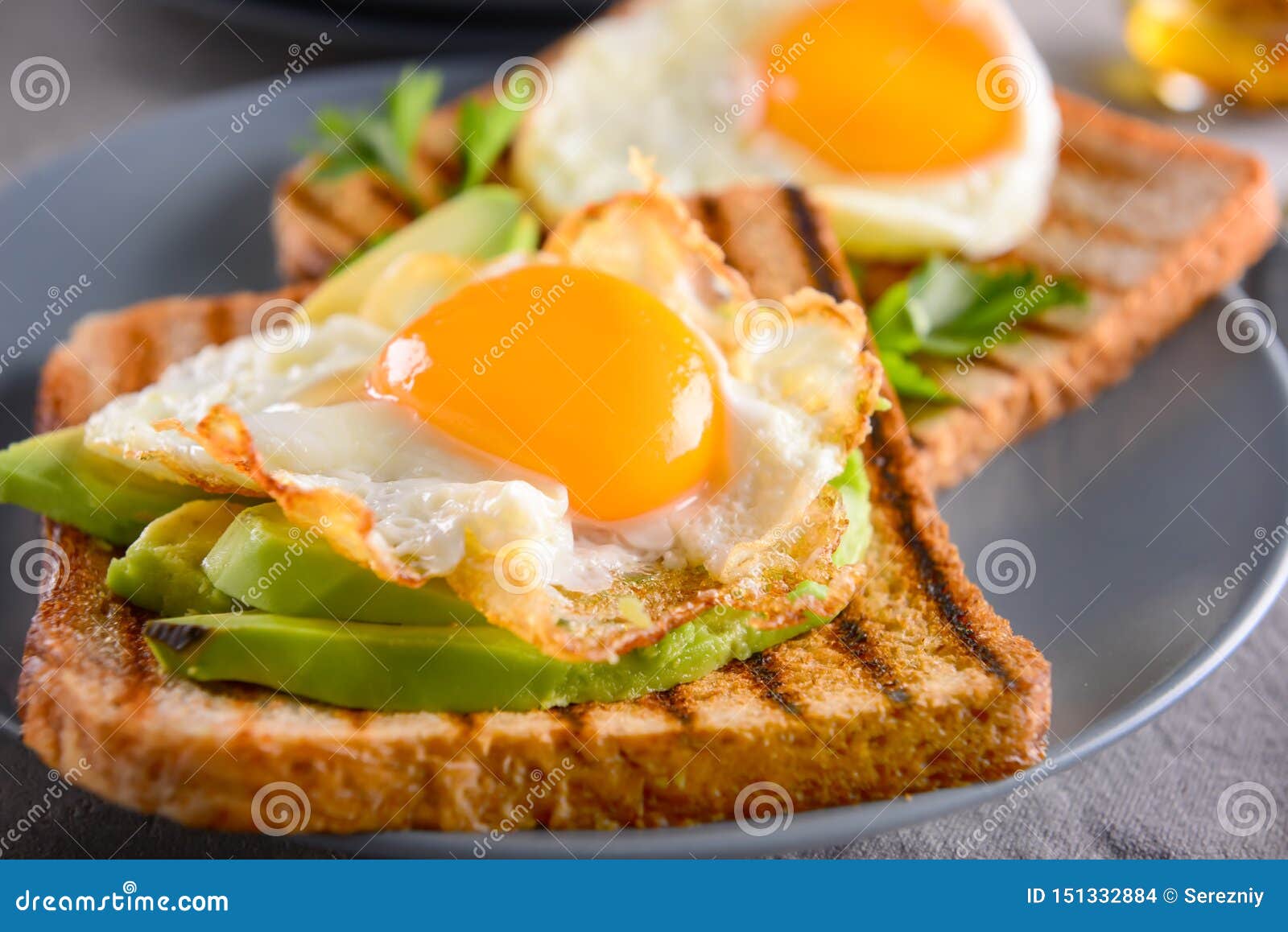 Toasted Bread with Tasty Fried Eggs and Avocado on Plate, Closeup Stock