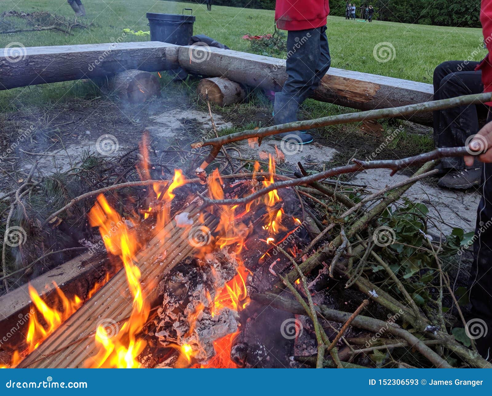 toasting 2 marshmallows on the end of sticks over a fire