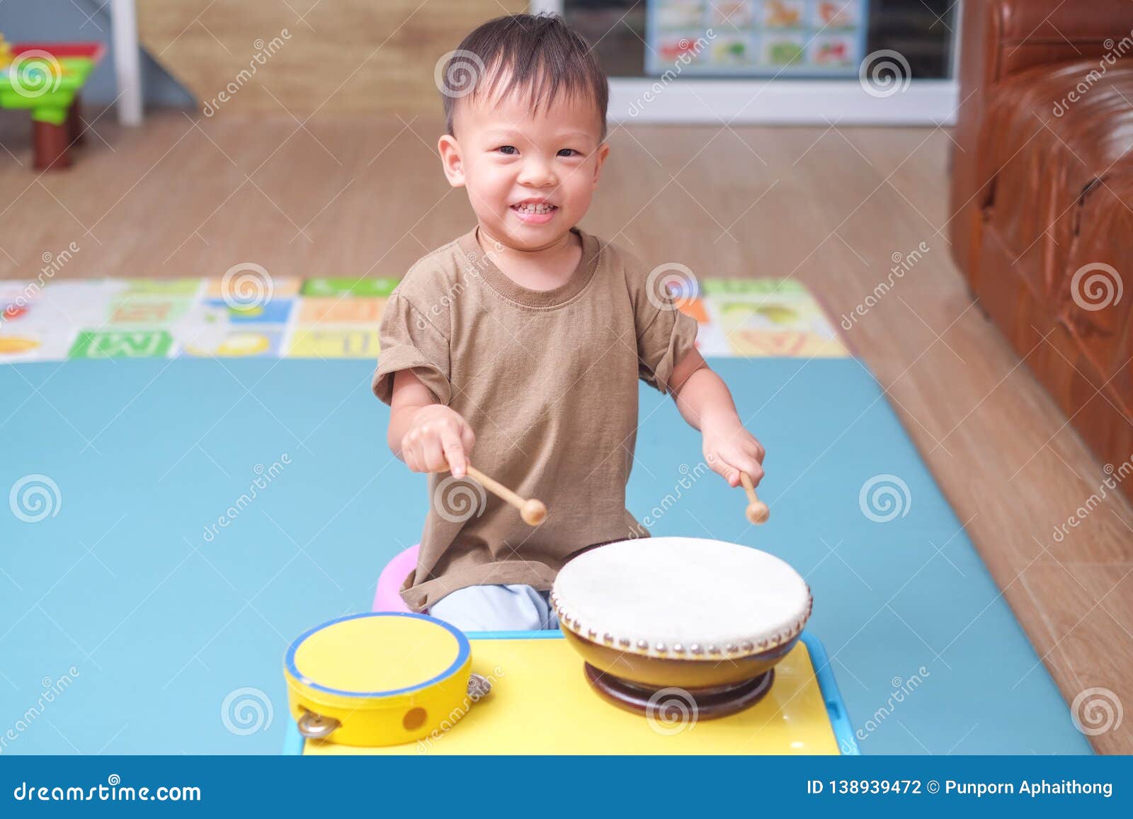 toddler baby boy child hold sticks & plays a musical instrument drum