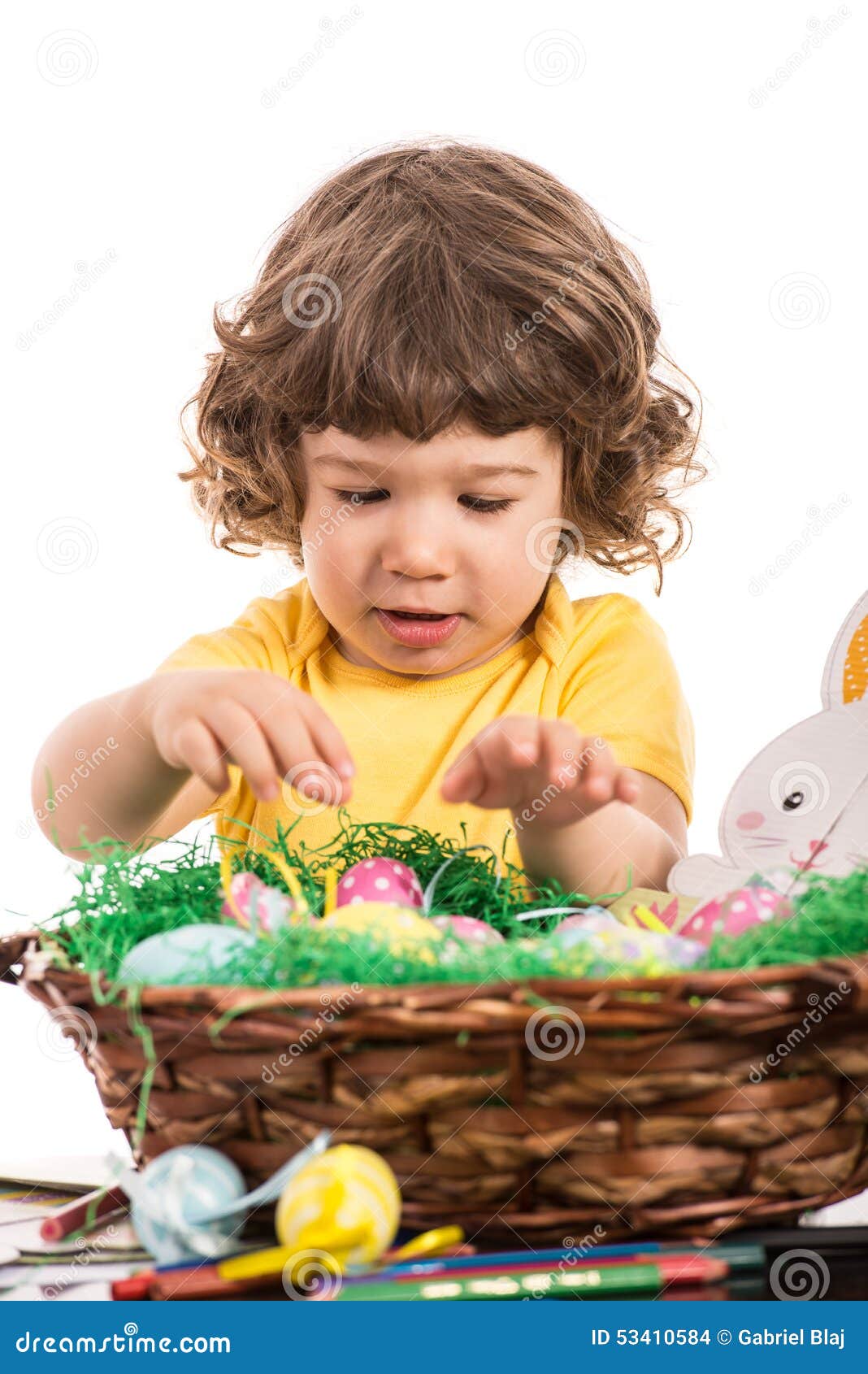 toddler boy arrange easter eggs in basket