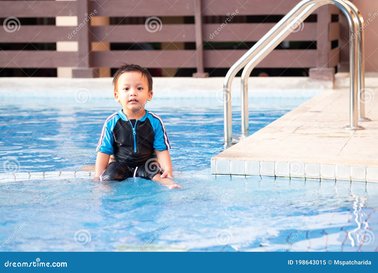 A Toddler Boy Sitting on the Edge of a Swimming Pool Stock Image