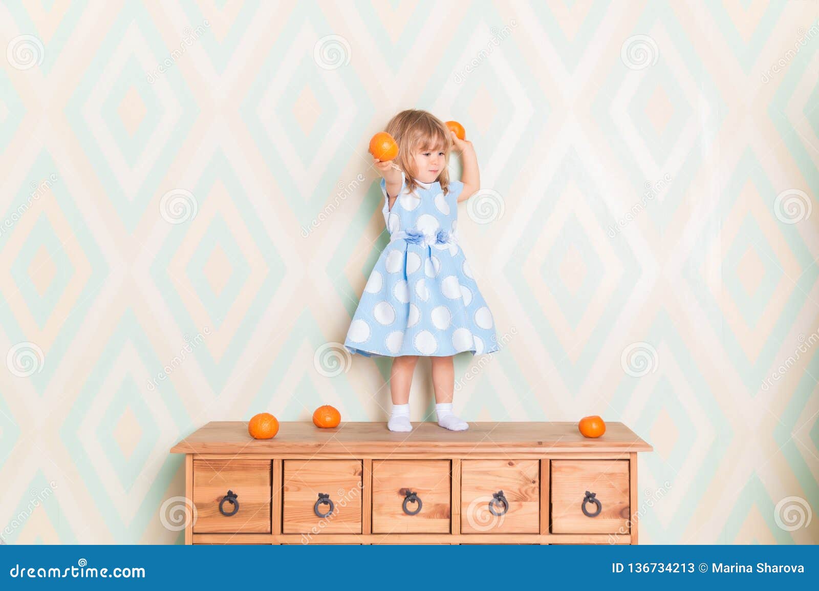 Toddler Child Girl In Blue Dress Standing On Wooden Chest Of