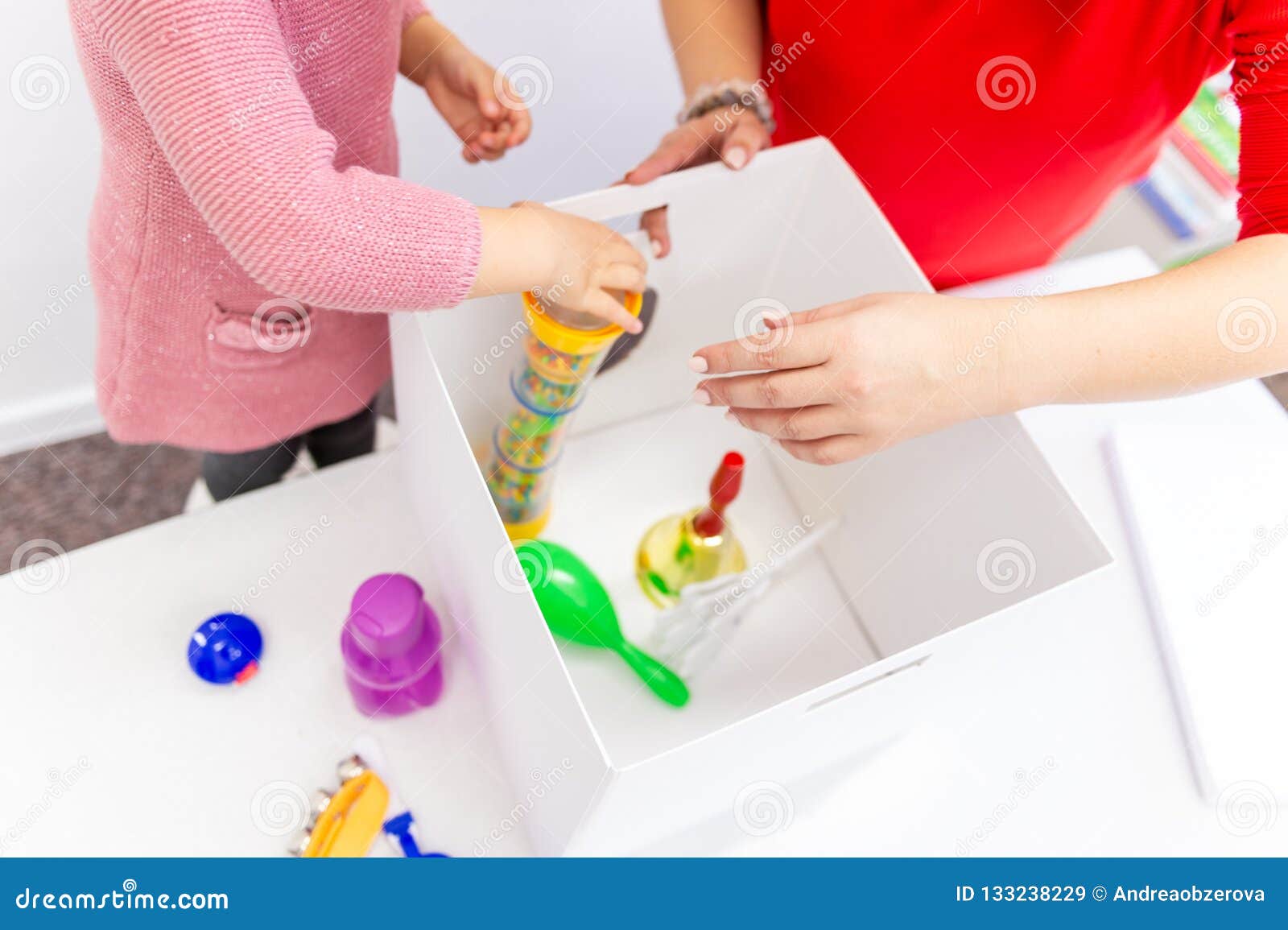 toddler girl in child occupational therapy session doing sensory playful exercises with her therapist.