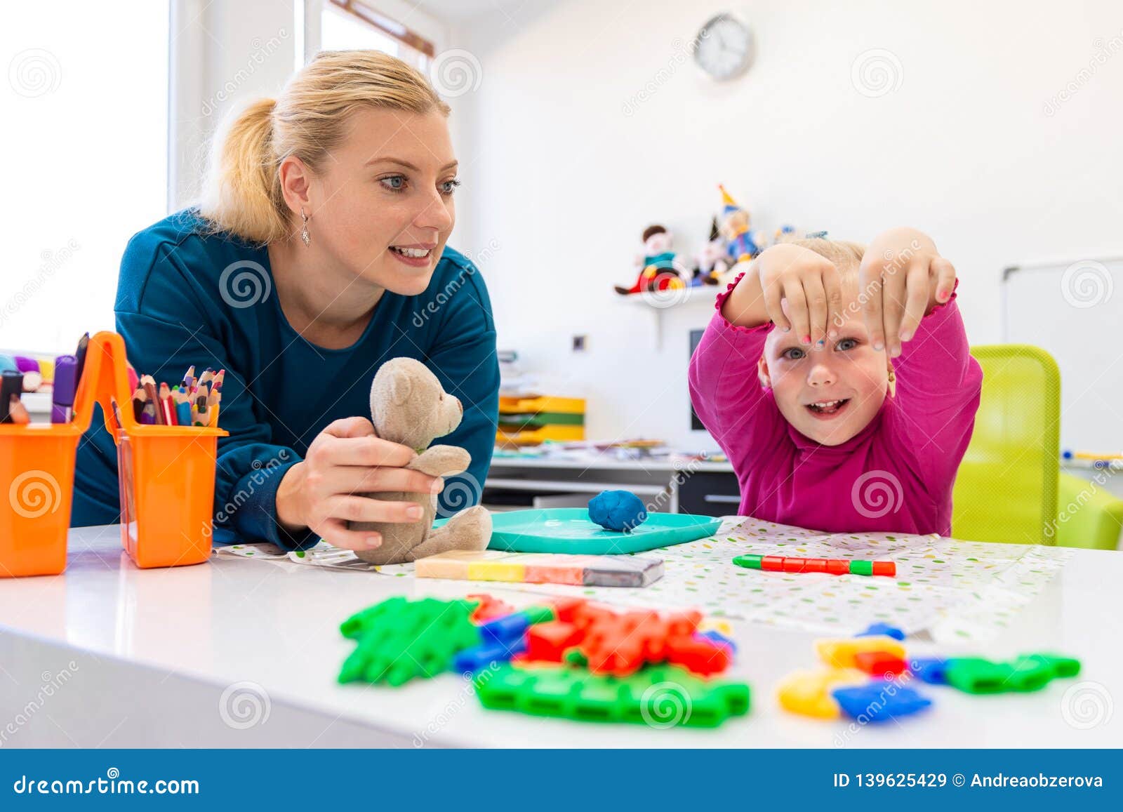 toddler girl in child occupational therapy session doing sensory playful exercises with her therapist.