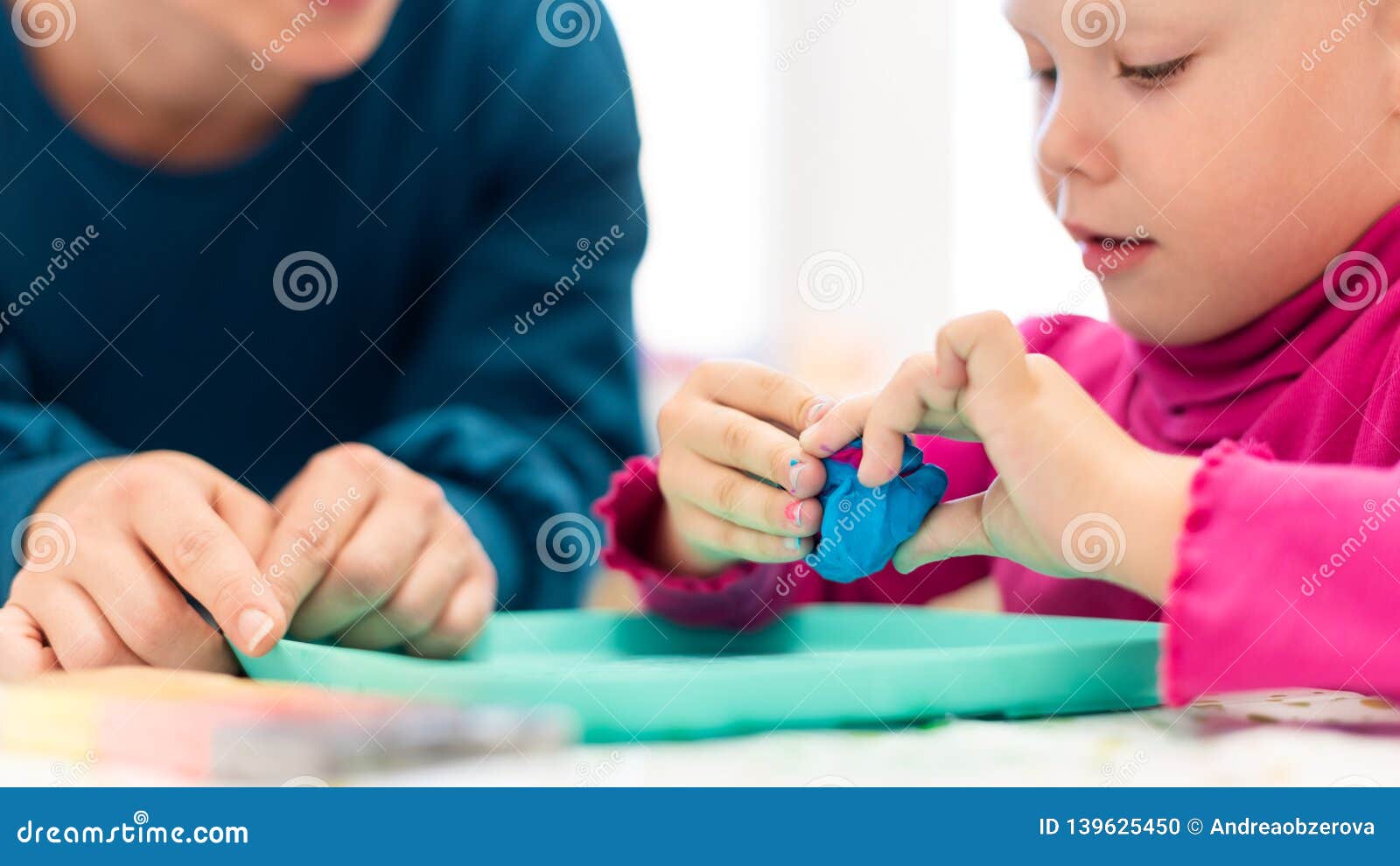 toddler girl in child occupational therapy session doing sensory playful exercises with her therapist.