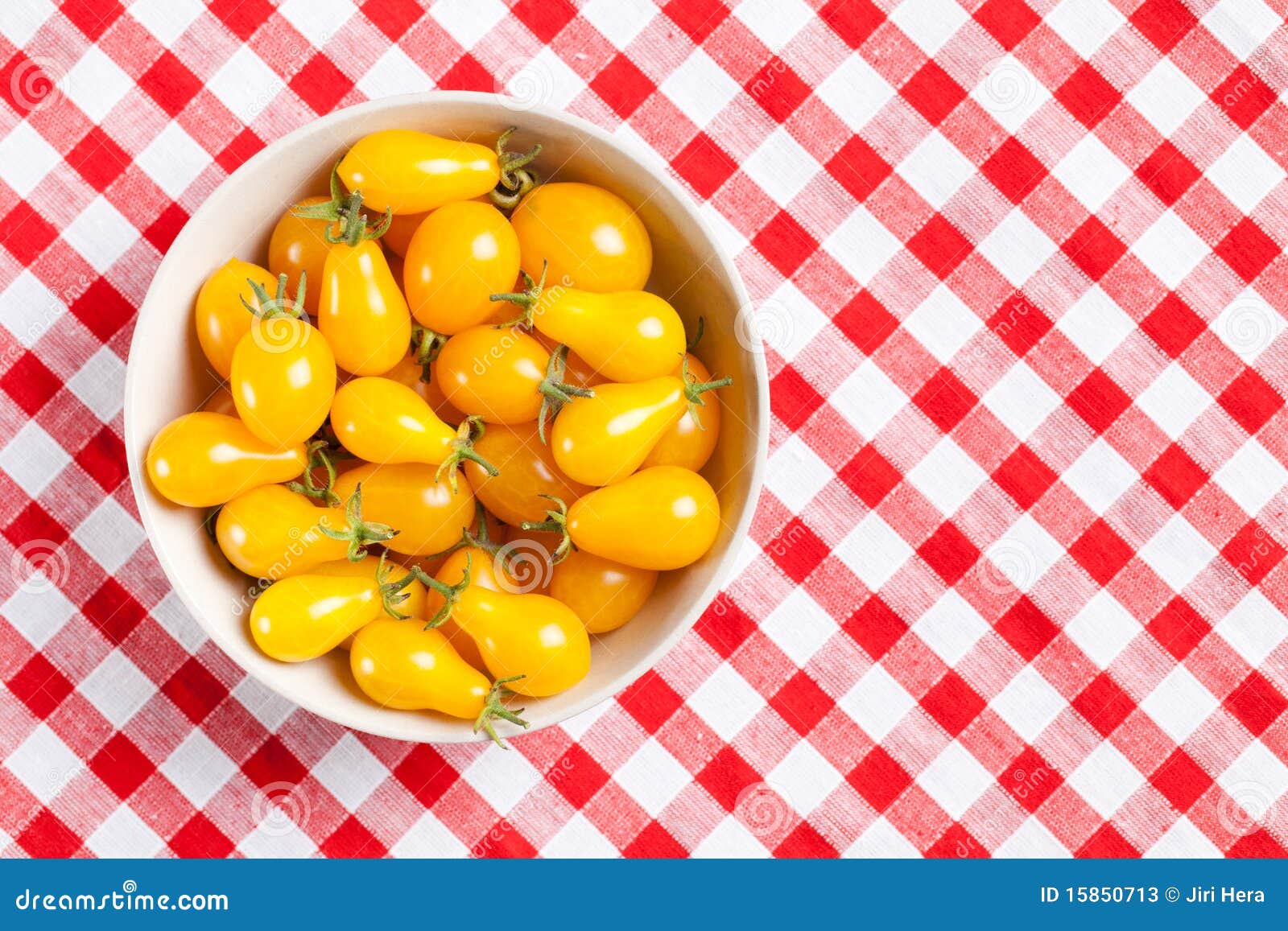 La foto tiró de tomates amarillos en mantel de la comida campestre