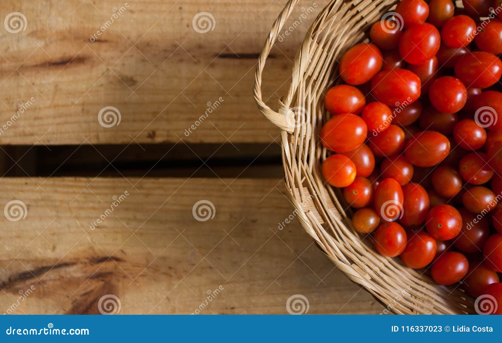 tomates-cereja vermelhos pequenos dentro de cesta caixote de madeira em estilo rÃÂºstico, foco seletivo