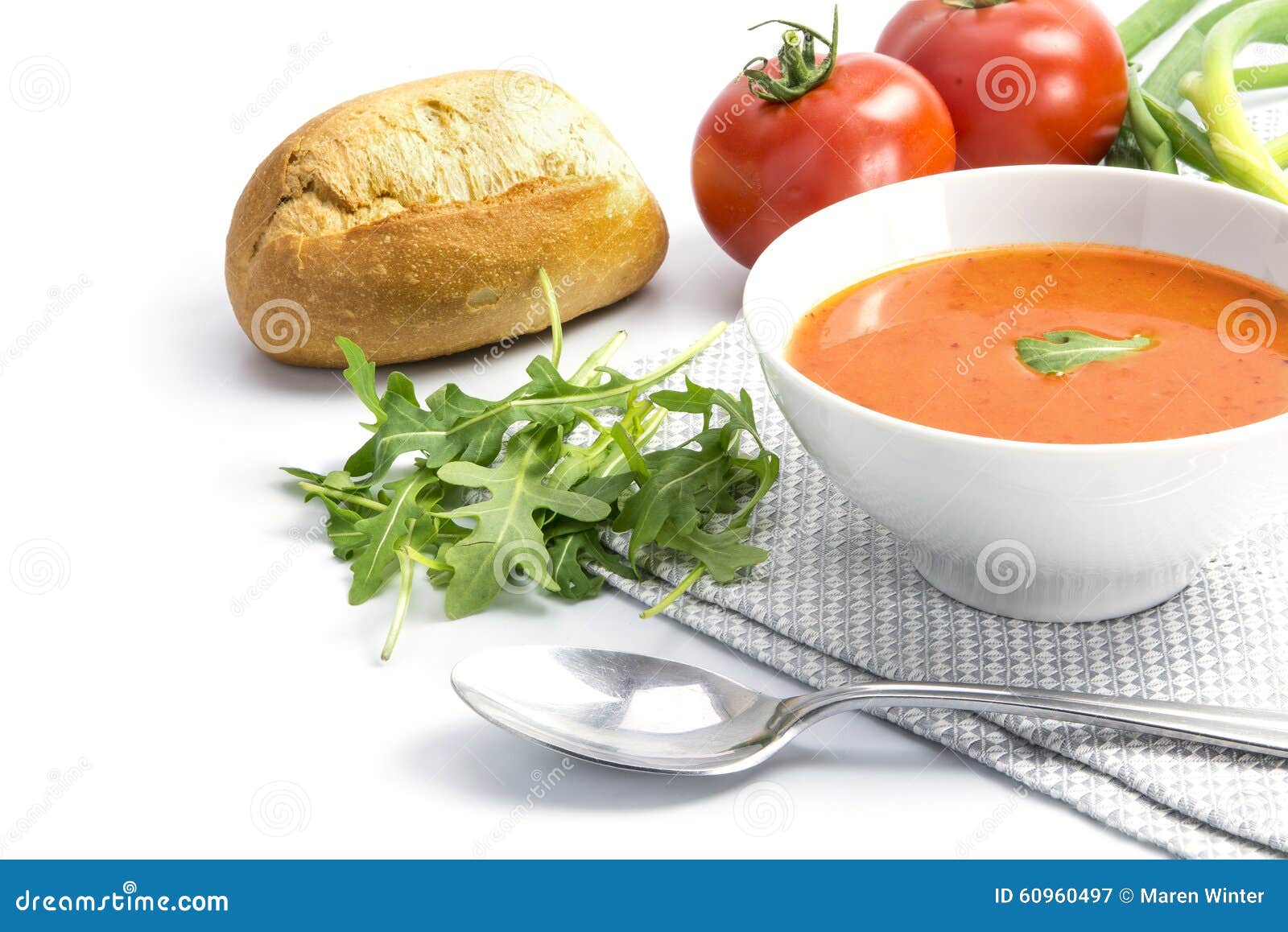 Tomato Soup in a Bowl with Bread Rolls and Arugula on a White Ba Stock