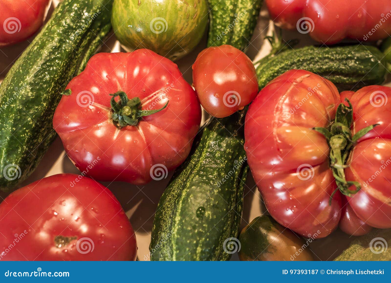 Tomatoe und Gurke auf Erzeugnisdeutschland-Makronahaufnahme des organischen Biohinterhofes des Holztischs gesunder im Freien
