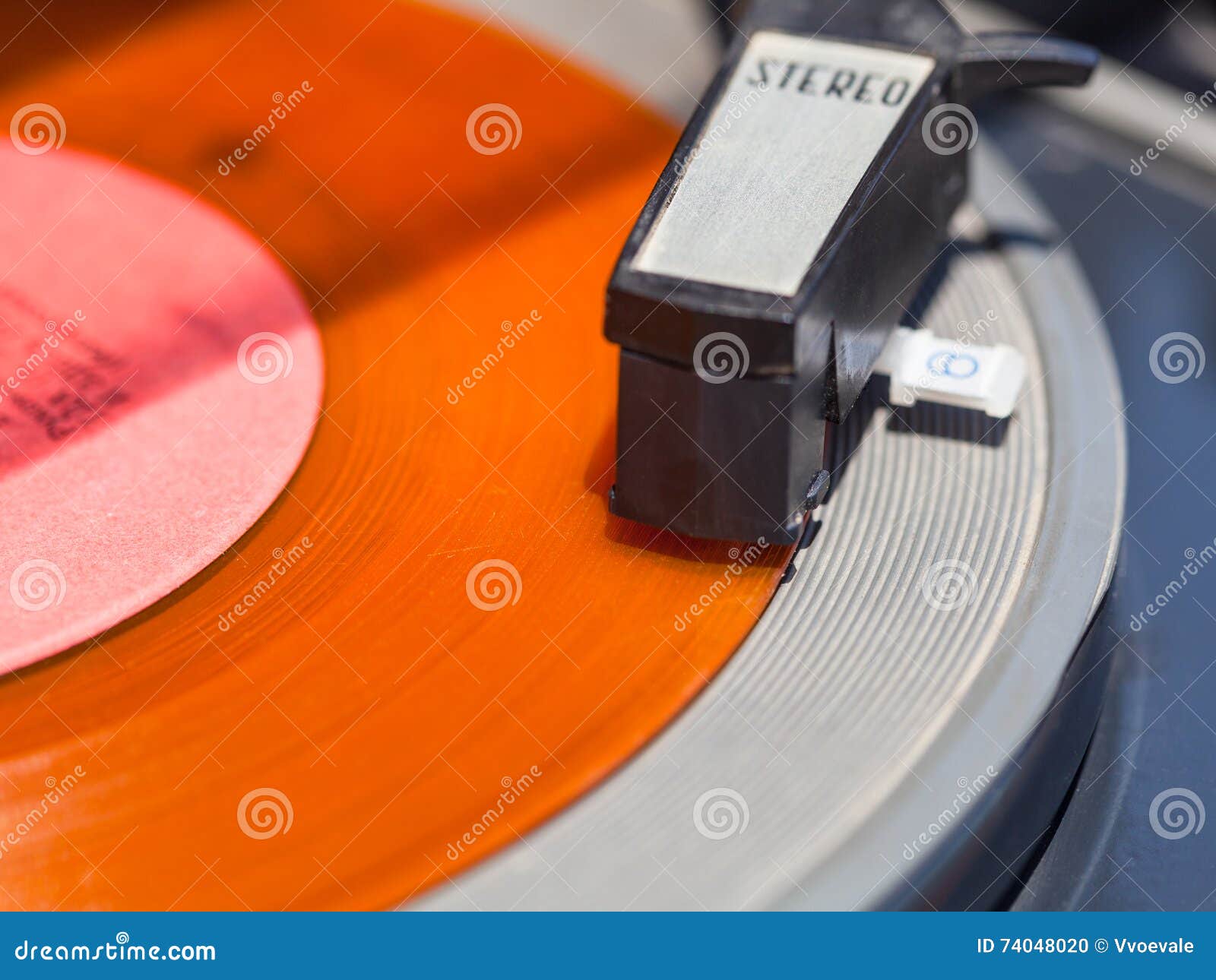 tonearm of record-player on orange vinyl disc