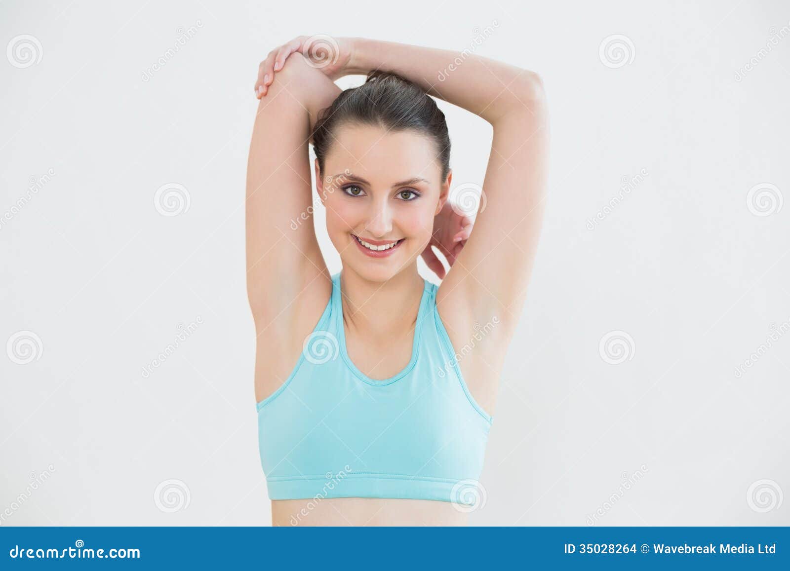 Photo about Portrait of a toned young woman stretching hands behind head ag...