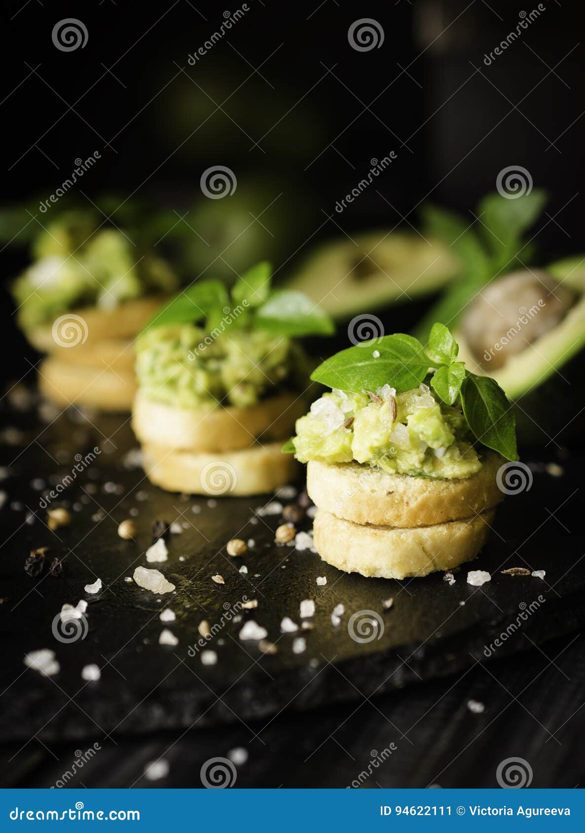 Toosts met deegwaren van avakado of guacamole en kruiden op een zwarte houten lijst met vruchten, selectieve nadruk, concept