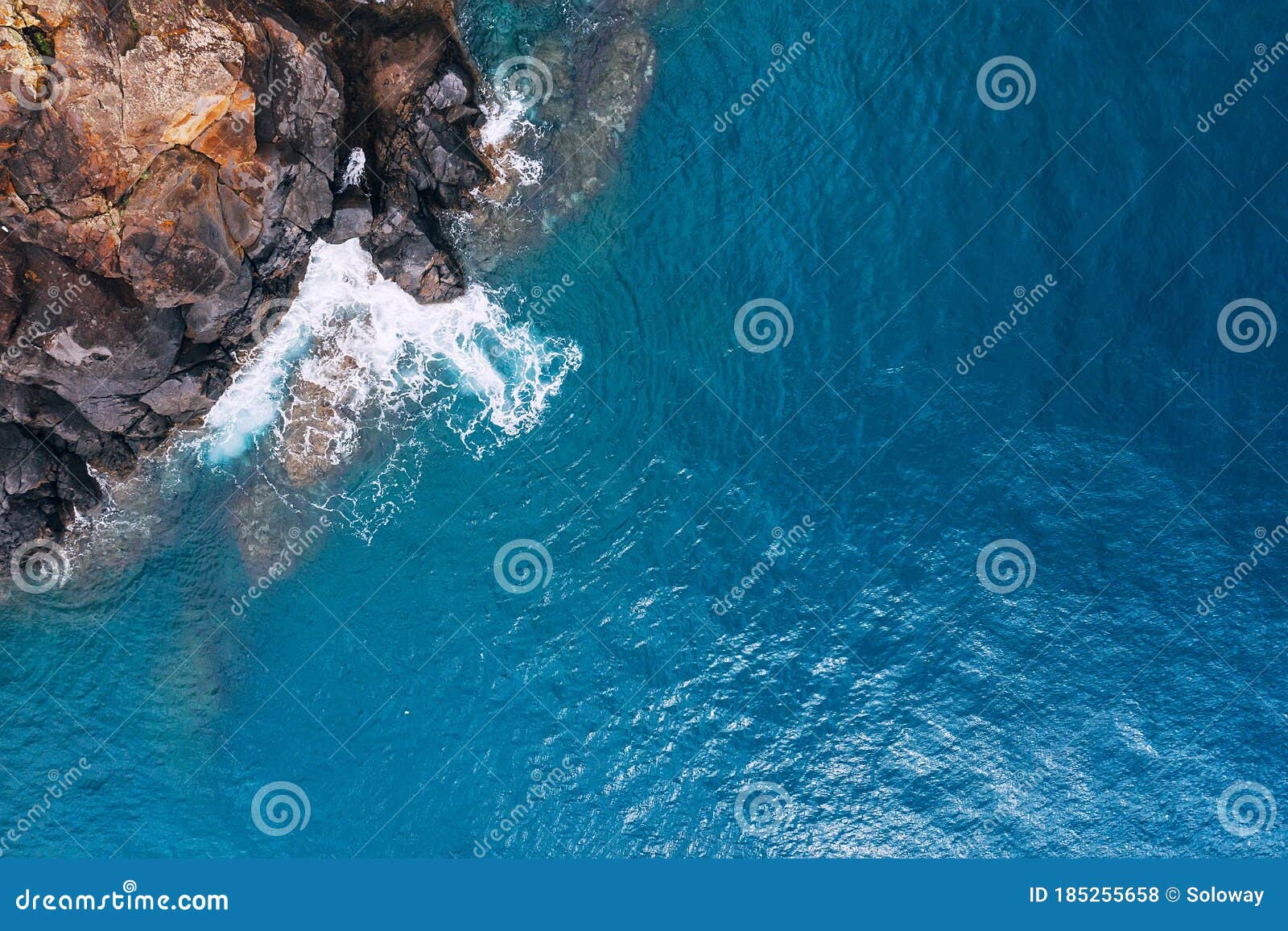 top aerial view of turquoise atlantic ocean water waves crashing on rocks on the portuguese madera island seashore