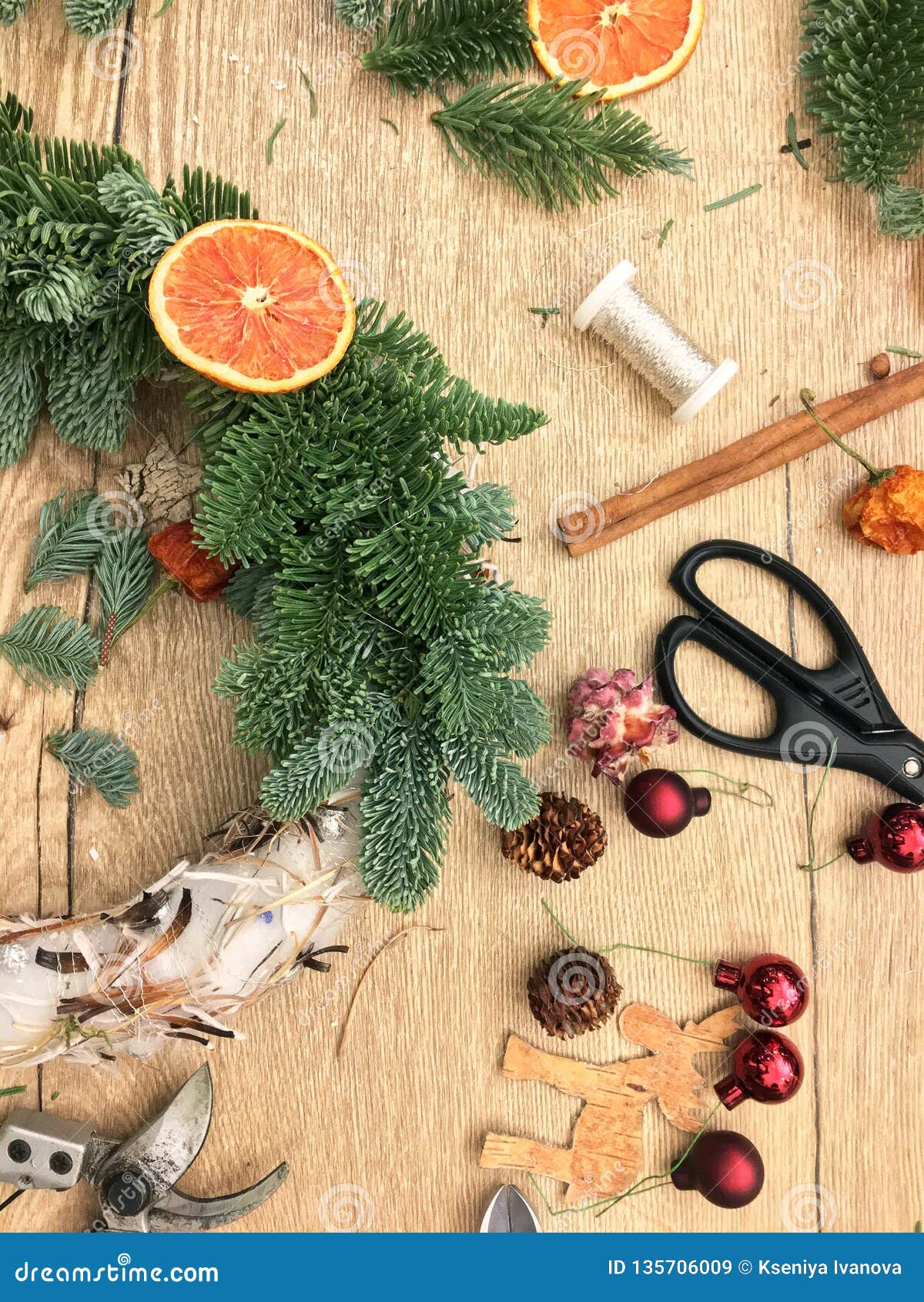 christmas tree decoration toys, gift box and scissors over rustic wood table background, top view.