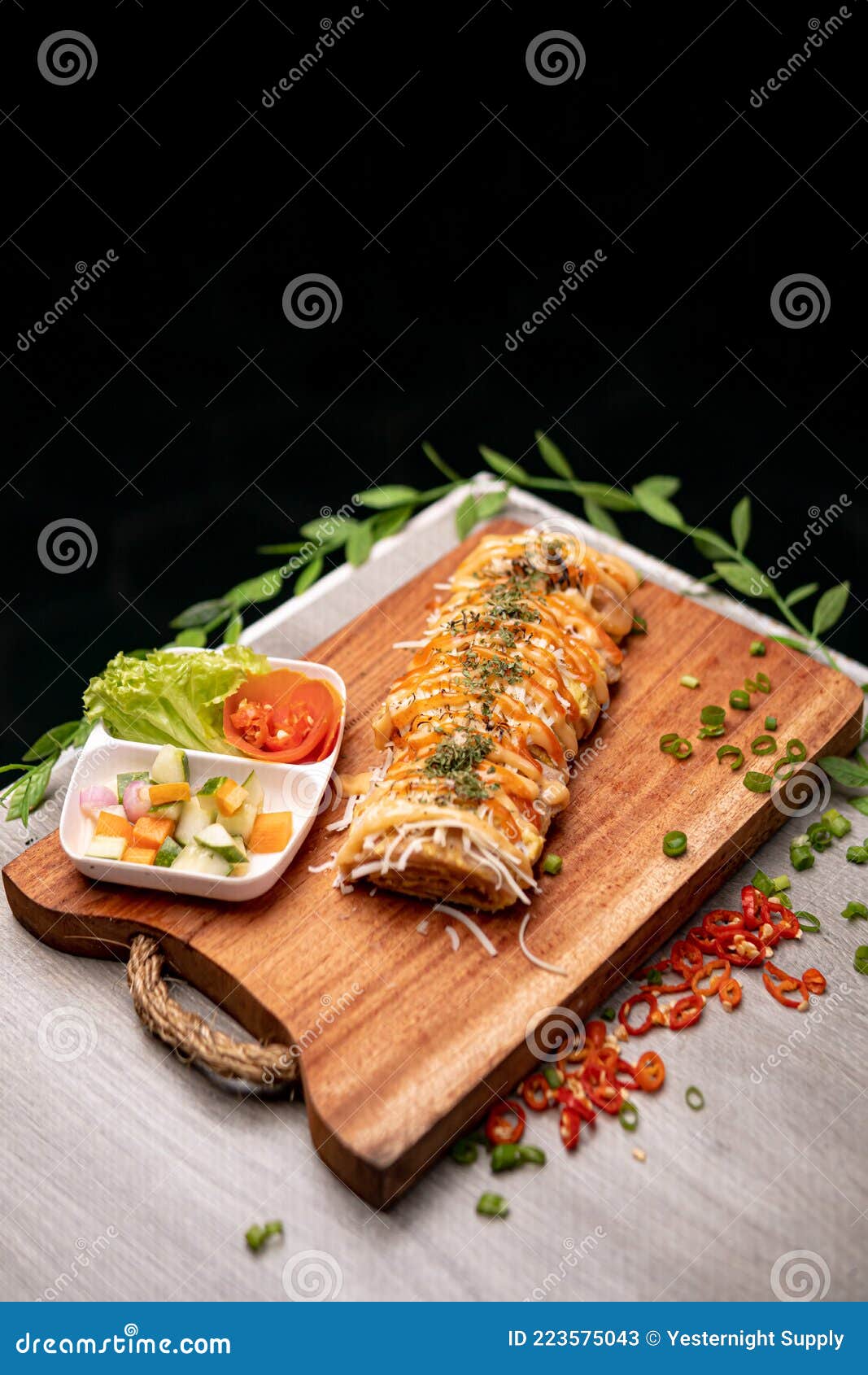 top side view of a fancy eggroll with herbs, spices and vegetables on a chopping board