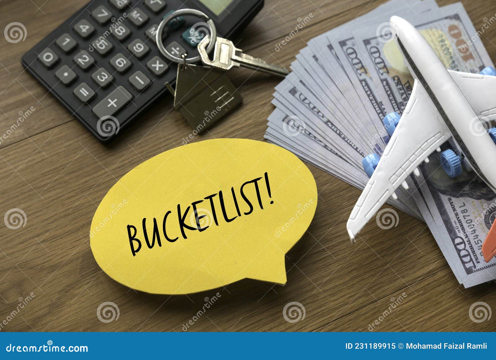top view of airplane model , money, house key, calculator and yellow speech burble written with bucketlist on wooden background
