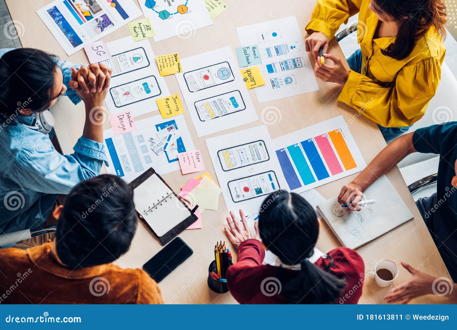 top view asian ux developer and ui er brainstorming about mobile app interface wireframe  on table with customer brief