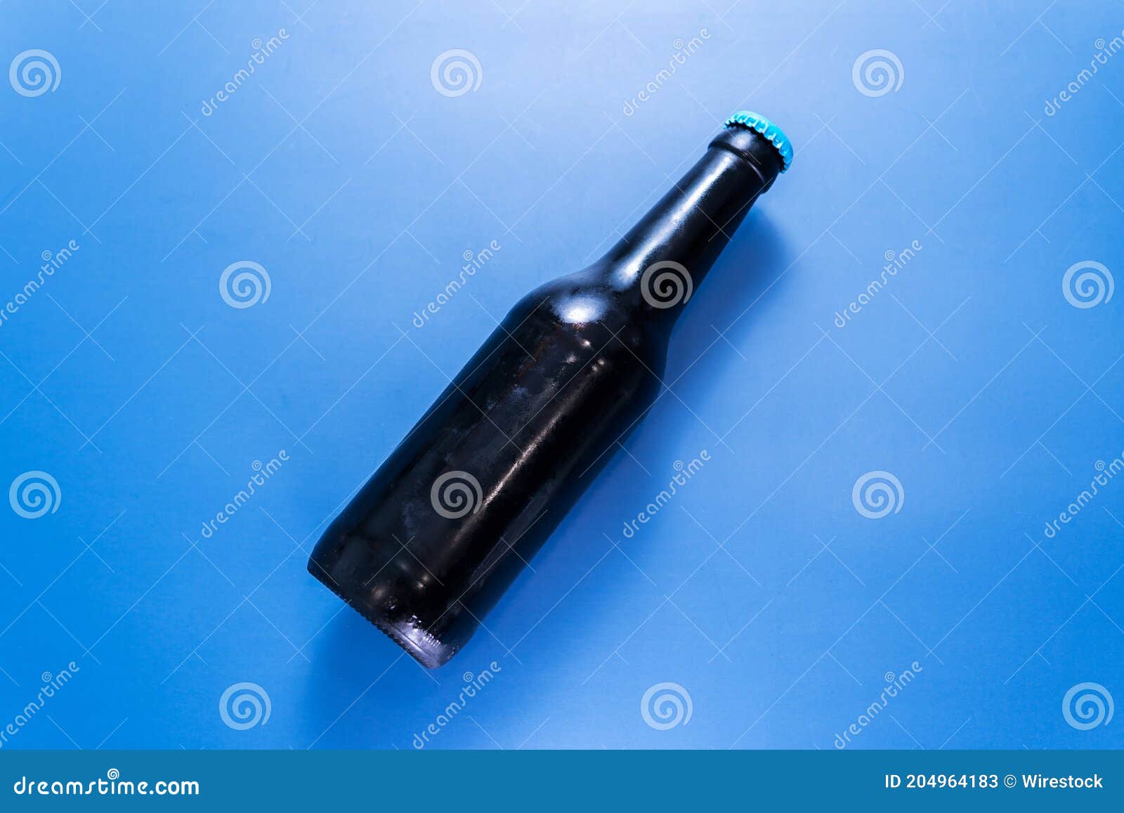 A top view of a black beer bottle on a blue surface