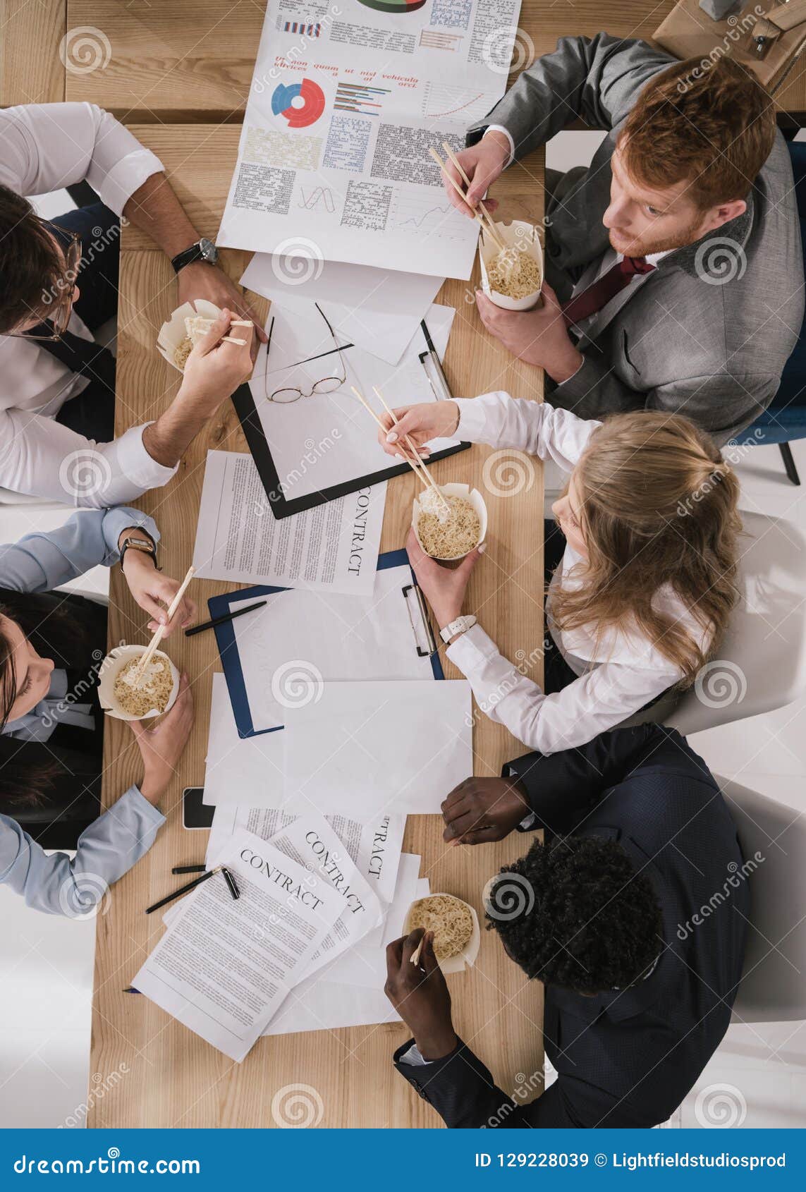 top view of businesspeople eating noodles while having paperwork