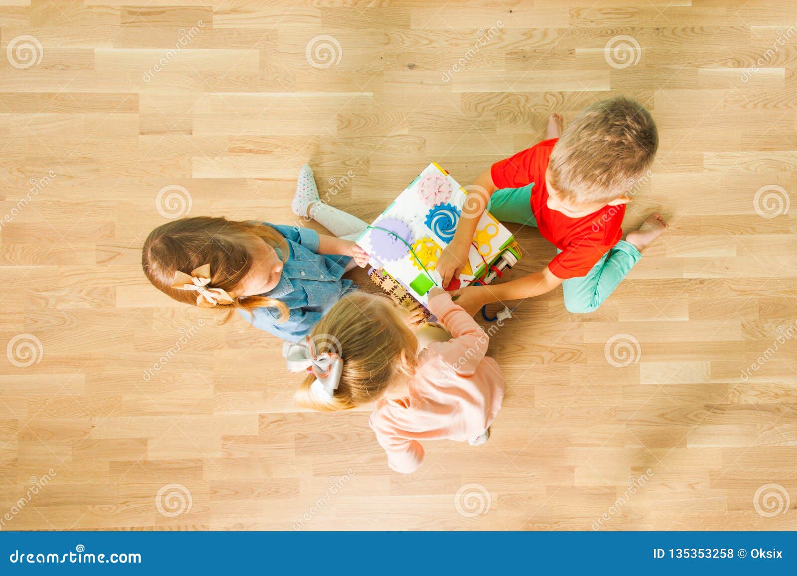 Top View Of Children Playing With Busy Board At Home Stock Photo