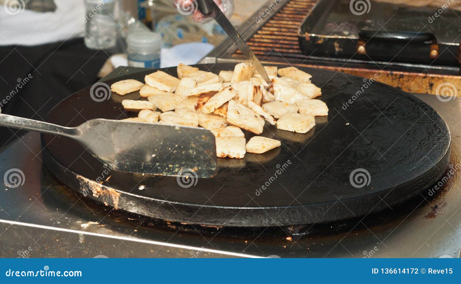 greek vender grilling ,squares of flatbread at a topical farmers market