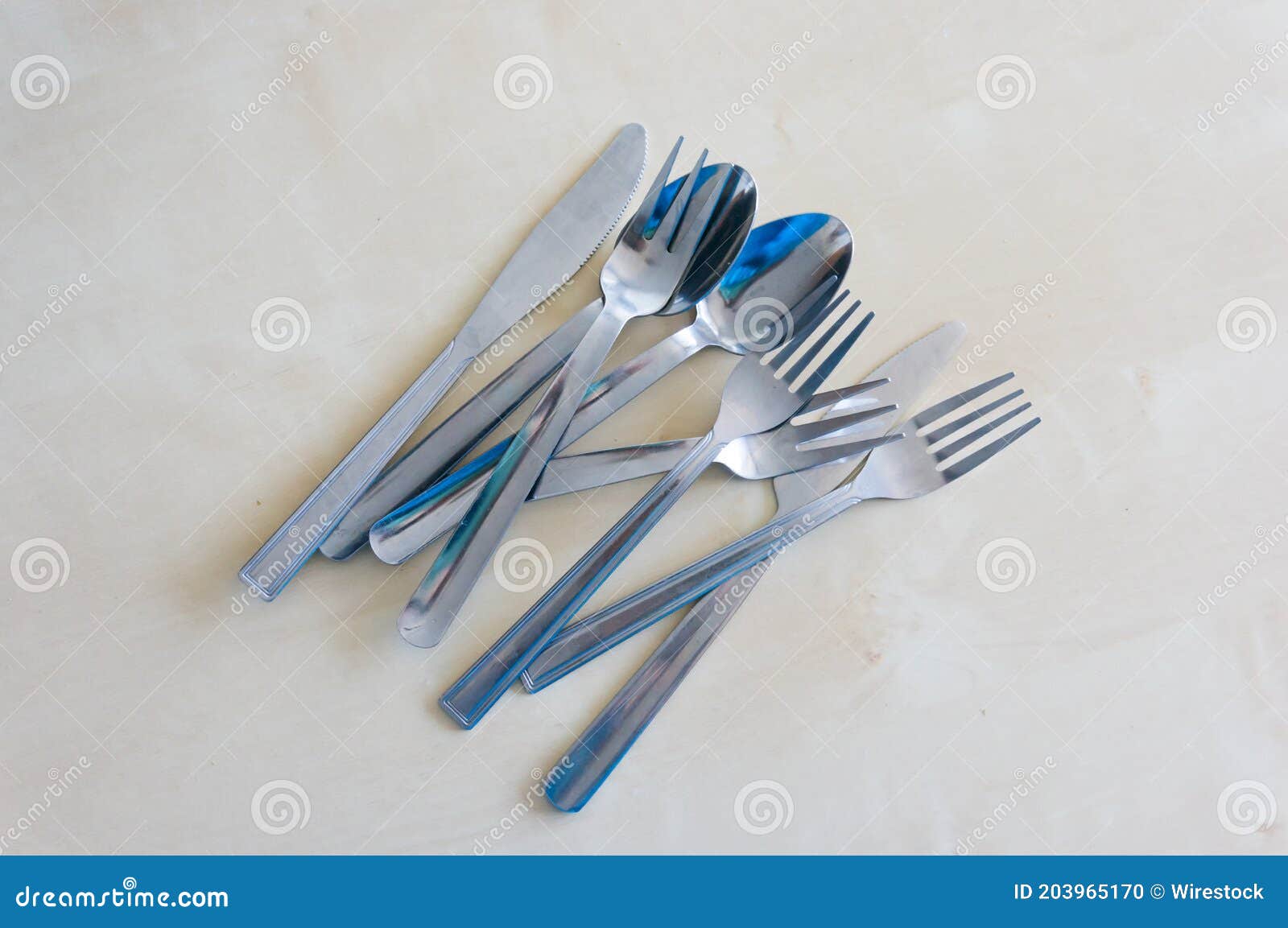 top view closeup of tablewares including forks, knives and spoons on a white table