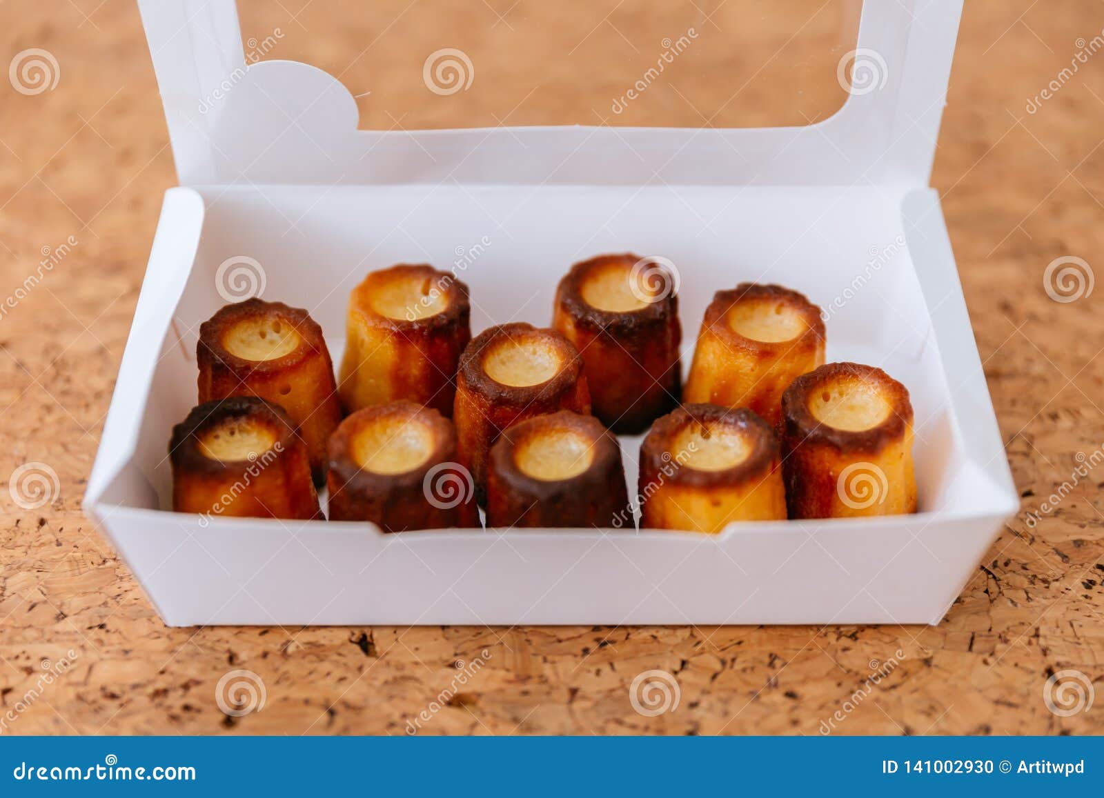 top view of fresh baked canelÃÂ©s inside white paper box. a small french pastry flavored with rum and vanilla.