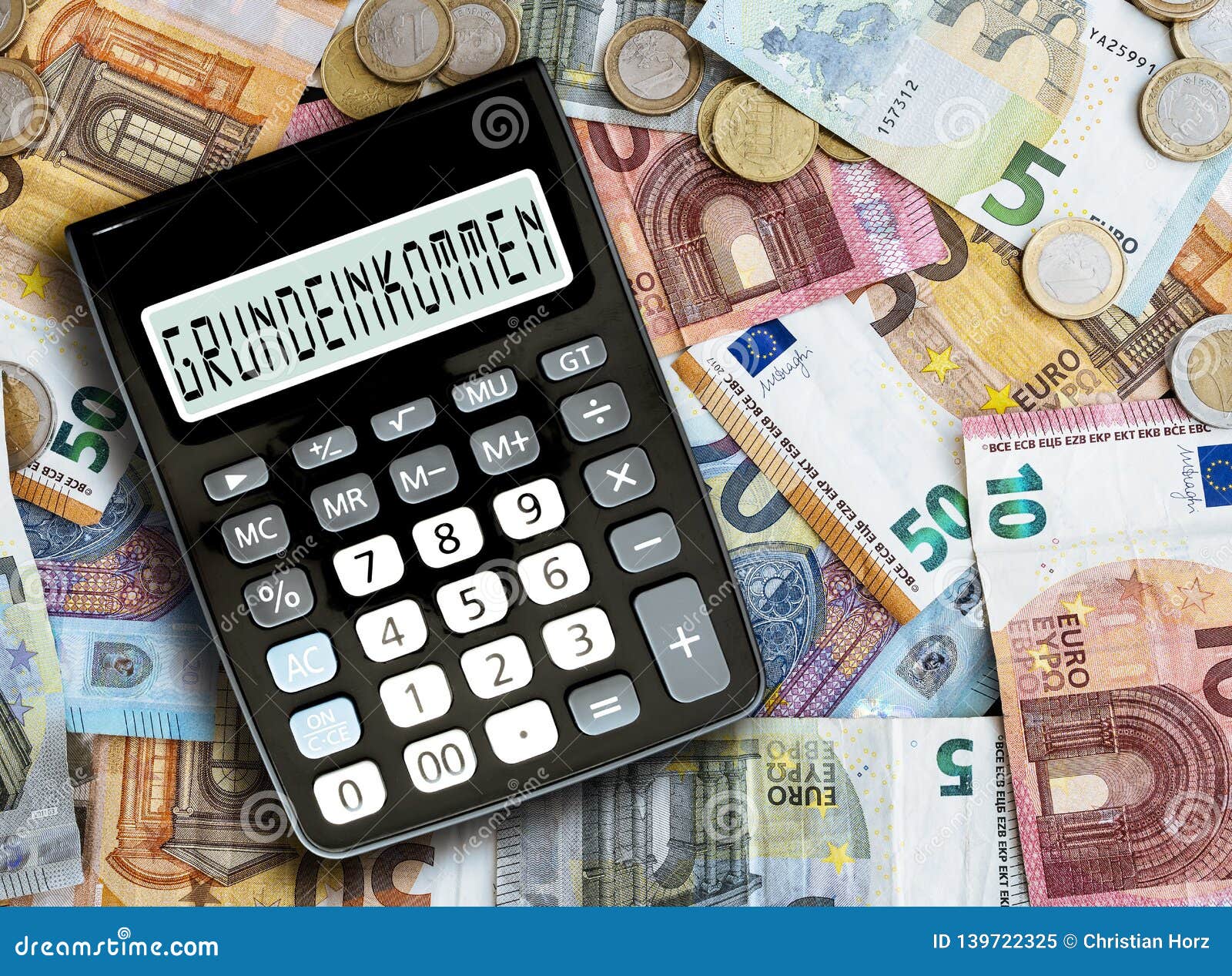 german word grundeinkommen basic income written on display of pocket calculator against cash money on table