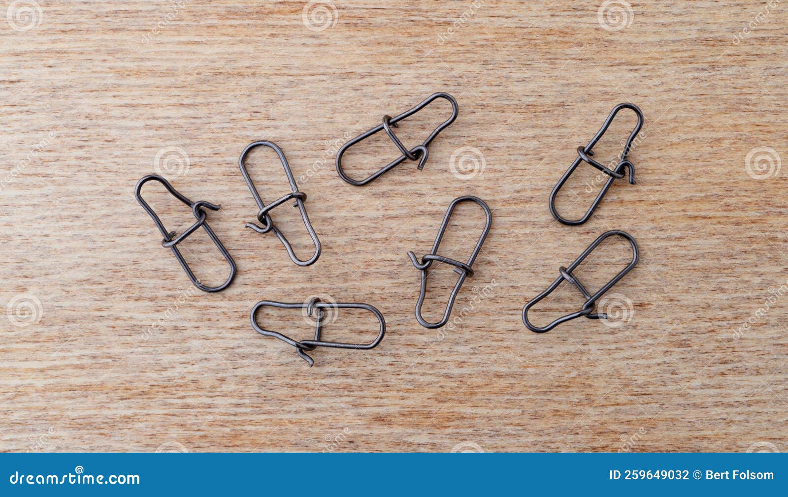 top view of a group of lock snaps used for fishing leaders on a wood background