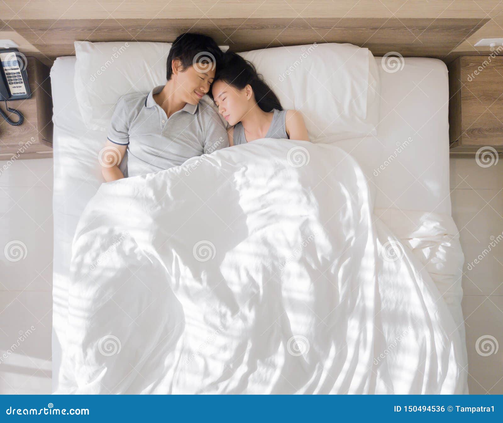 Top View of Happy Asian Couple Smiling, and Sleeping Together on Bed in Love and Sex Concept in a Modern Bedroom with White Stock Photo