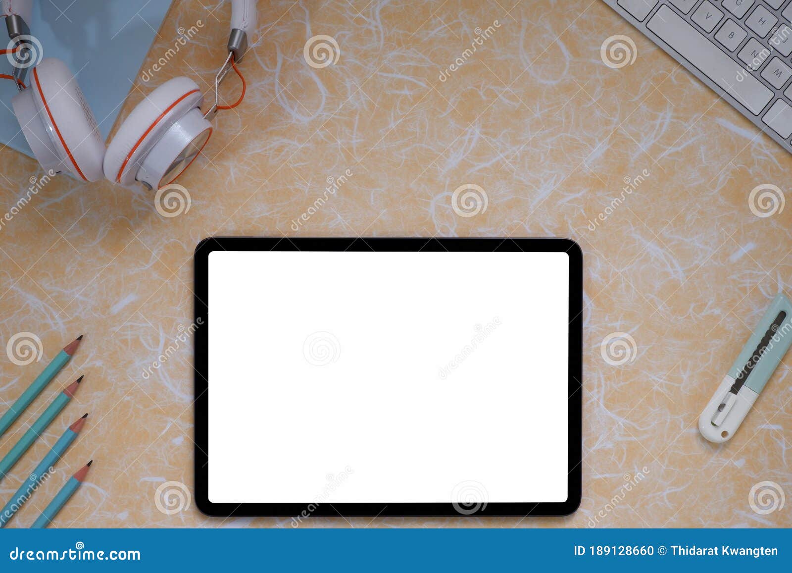 top view image of white blanks screen computer tablet with putting on colorful working desk and surrounded by pen, key borde,