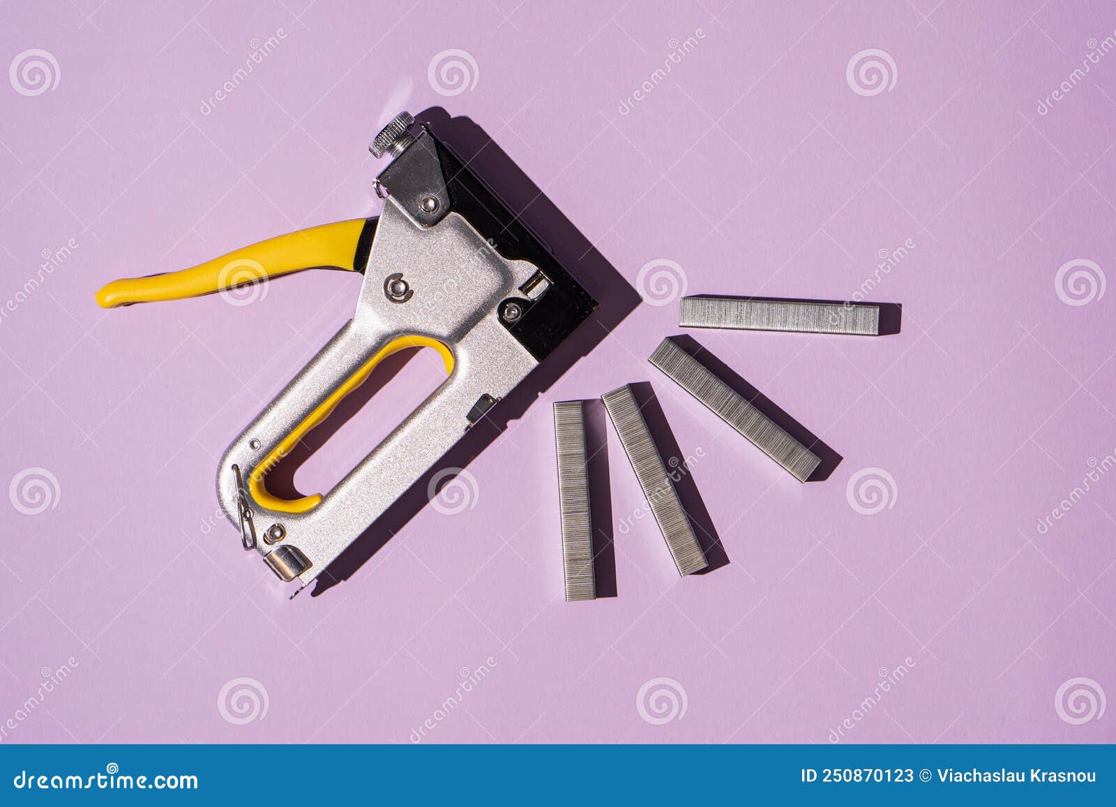 Top View of Yellow Mechanical Construction Stapler and Stapler Staples Lying on Purple