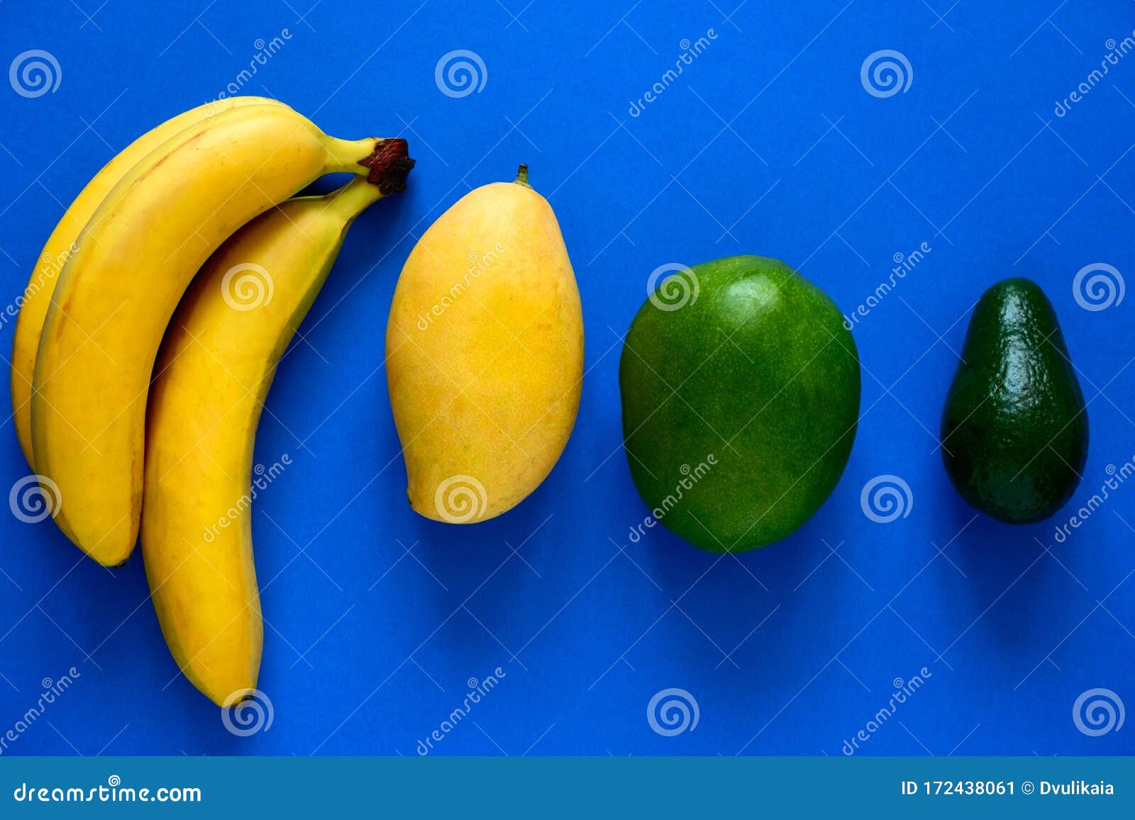 Layout of Fresh Bananas,mangoes and Avocado on a Blue Background Stock