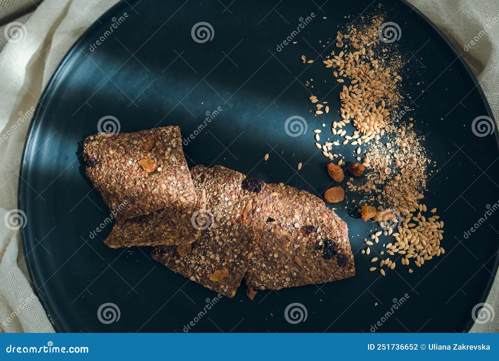 top view of linen breads with raisins, coriander grains and linen seads on a black plate